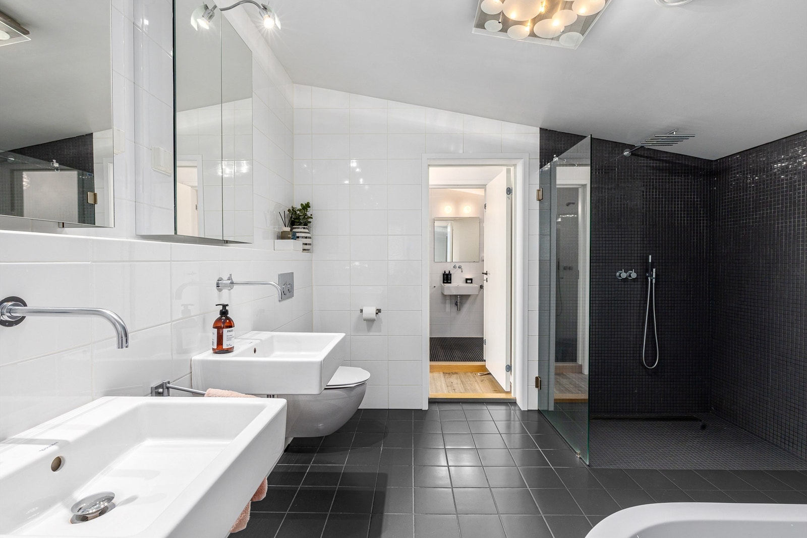 Hovedbadet er utstyrt med stor dusjnisje med glassvegg, badekar, to vegghengte servanter med speilskap, og et vegghengt toalett. Galleribilde