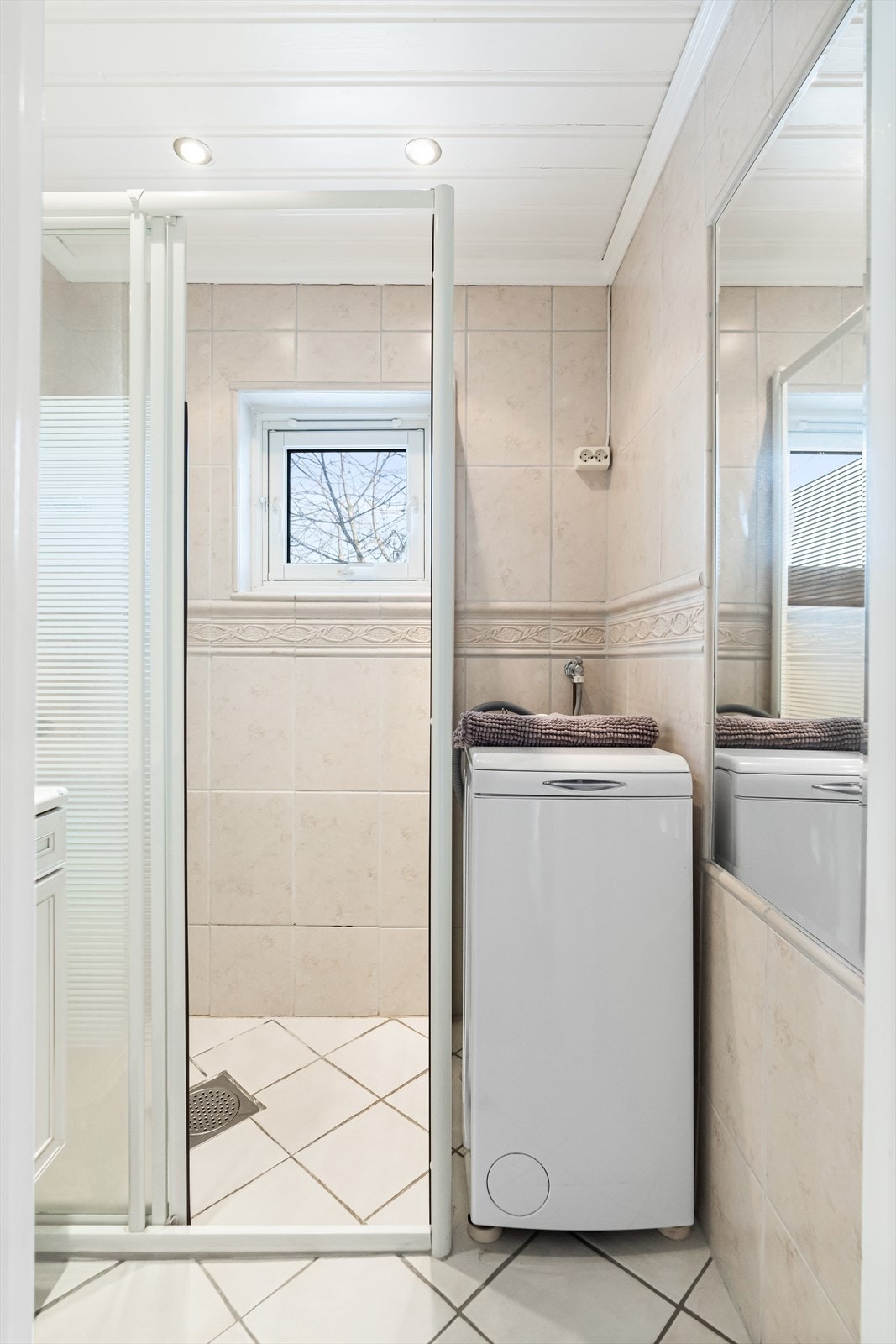 Badet er innredet med servant nedfelt i innredning, innfelt speil i vegg, dusjhjørne med glassdører og opplegg
for vaskemaskin. Galleribilde