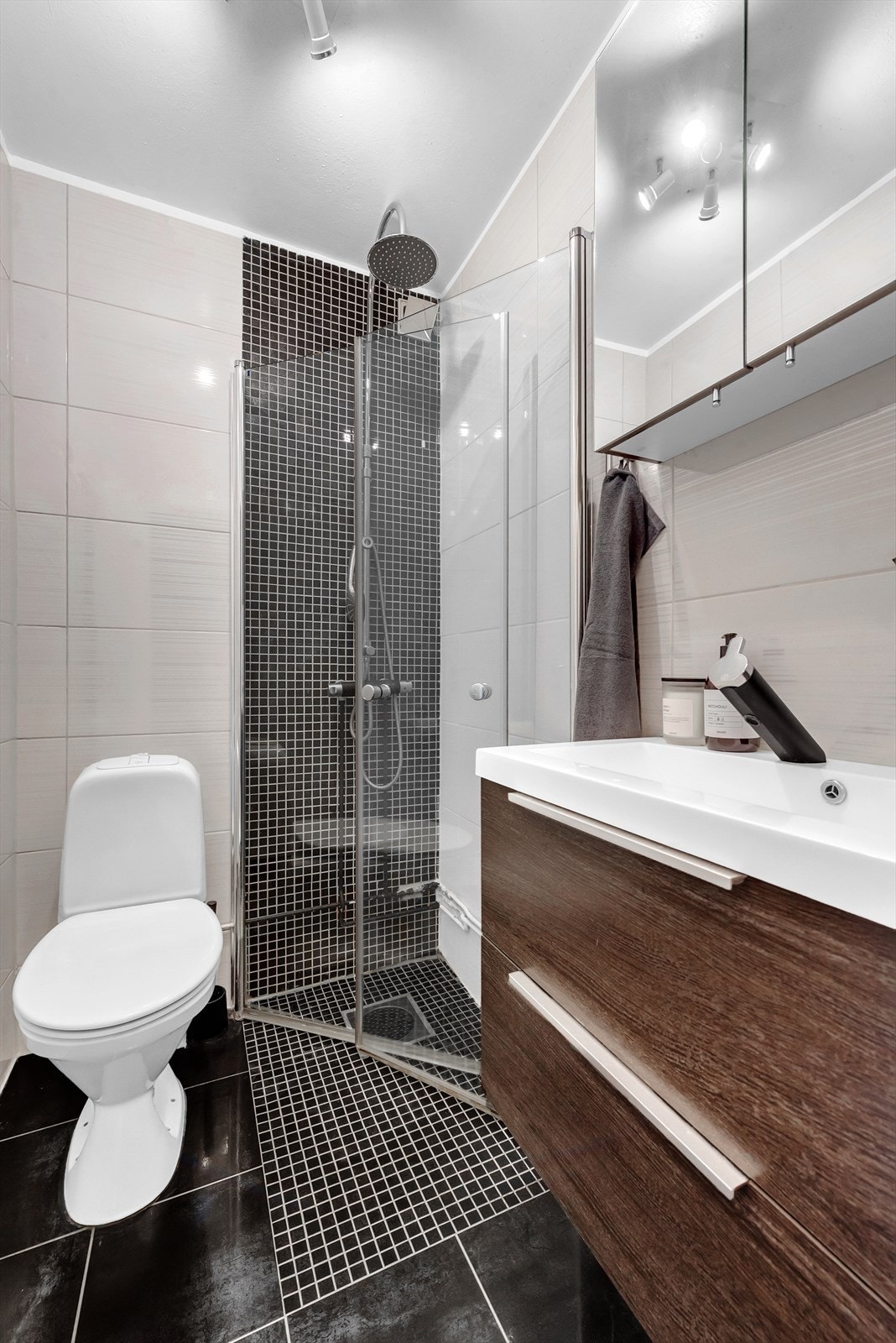 Badet består av dusj med innfellbare dører i herdet glass, servant i helstøpt plate og toalett. Galleribilde