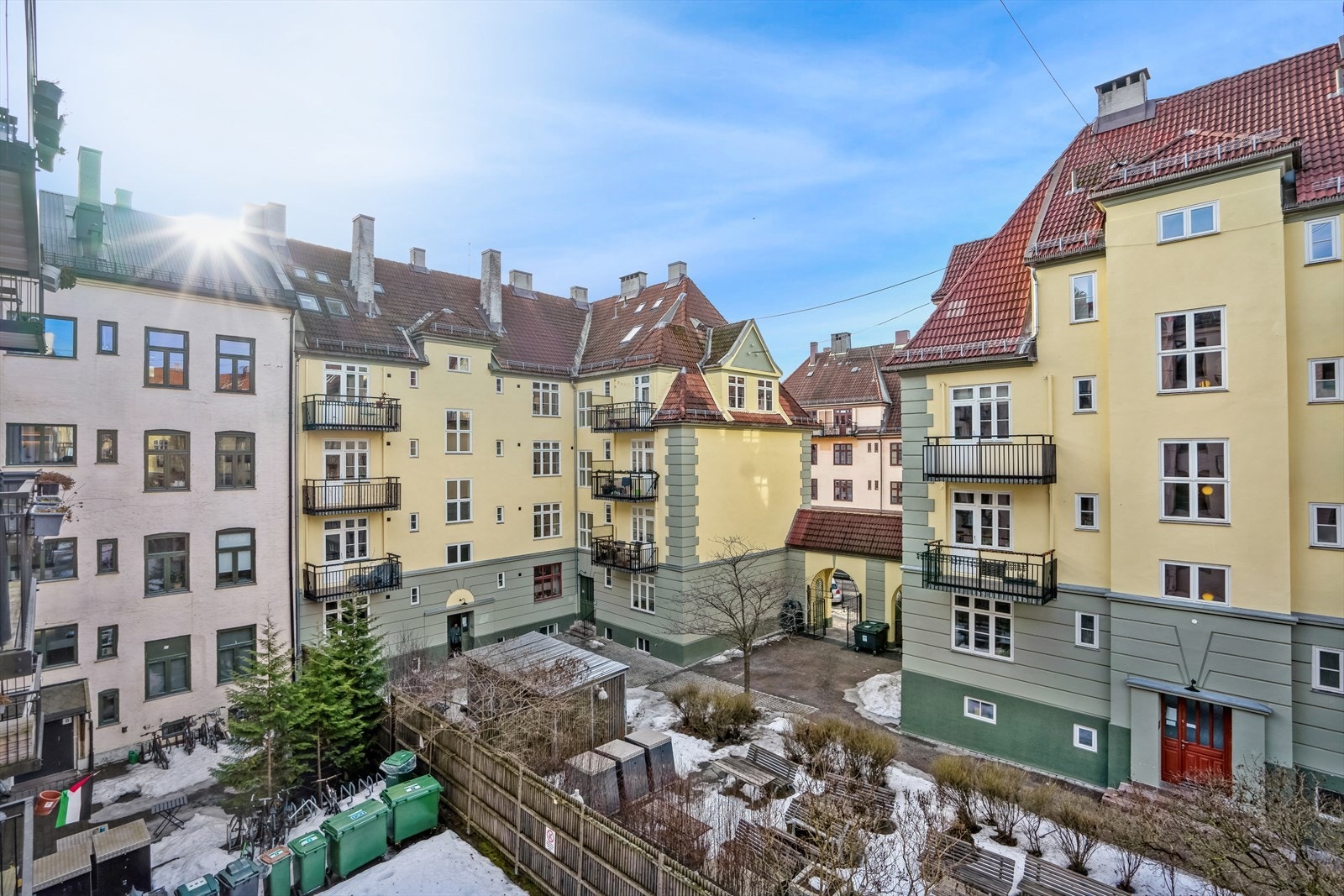 Opparbeidet gårdsrom med felles hage/gressplen, betongheller, sittegruppe og gjerde mot nabogårdsrom. Galleribilde