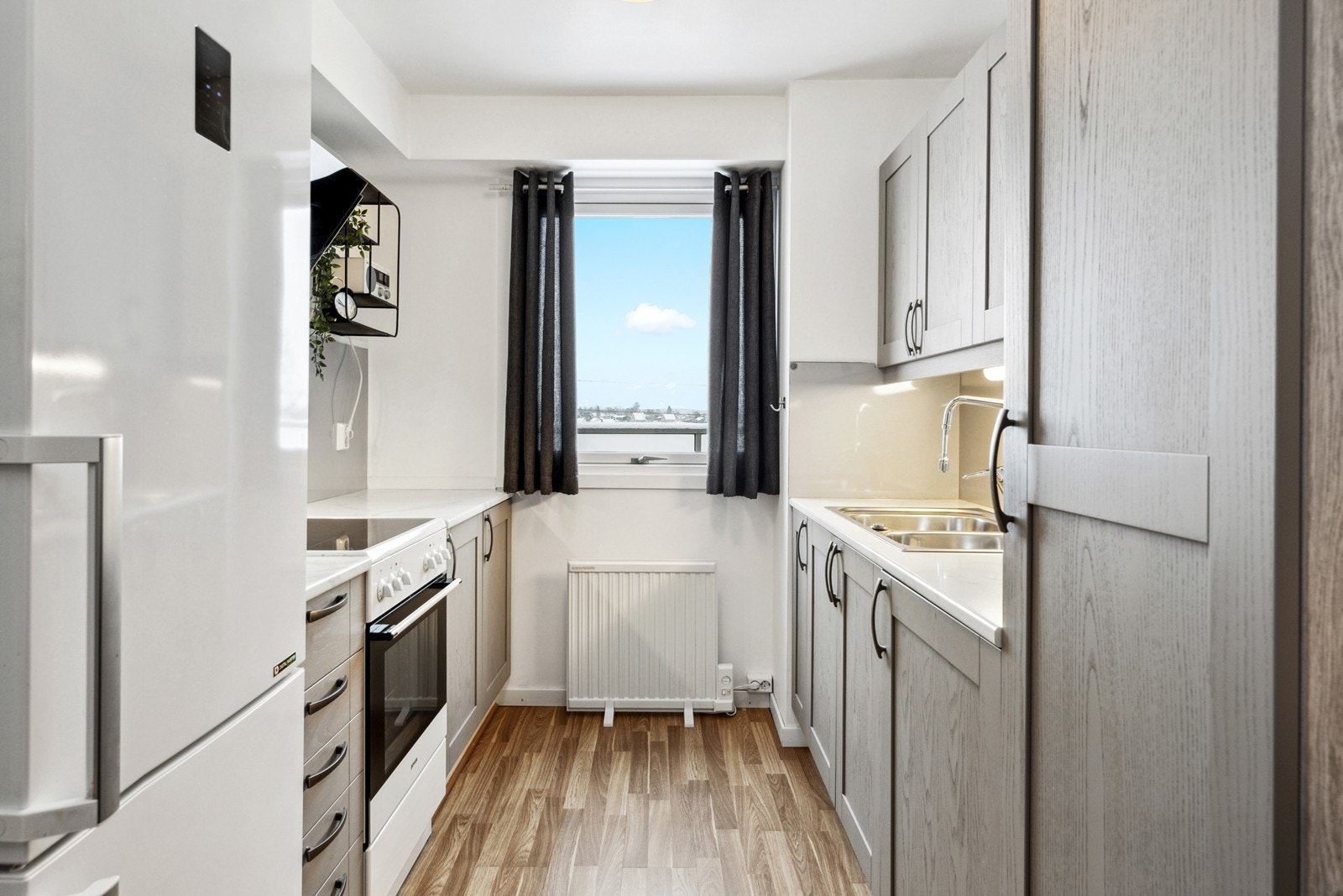 Kjøkkenet har innredning i treverk med glatte profilerte fronter og laminat benkeplate Galleribilde