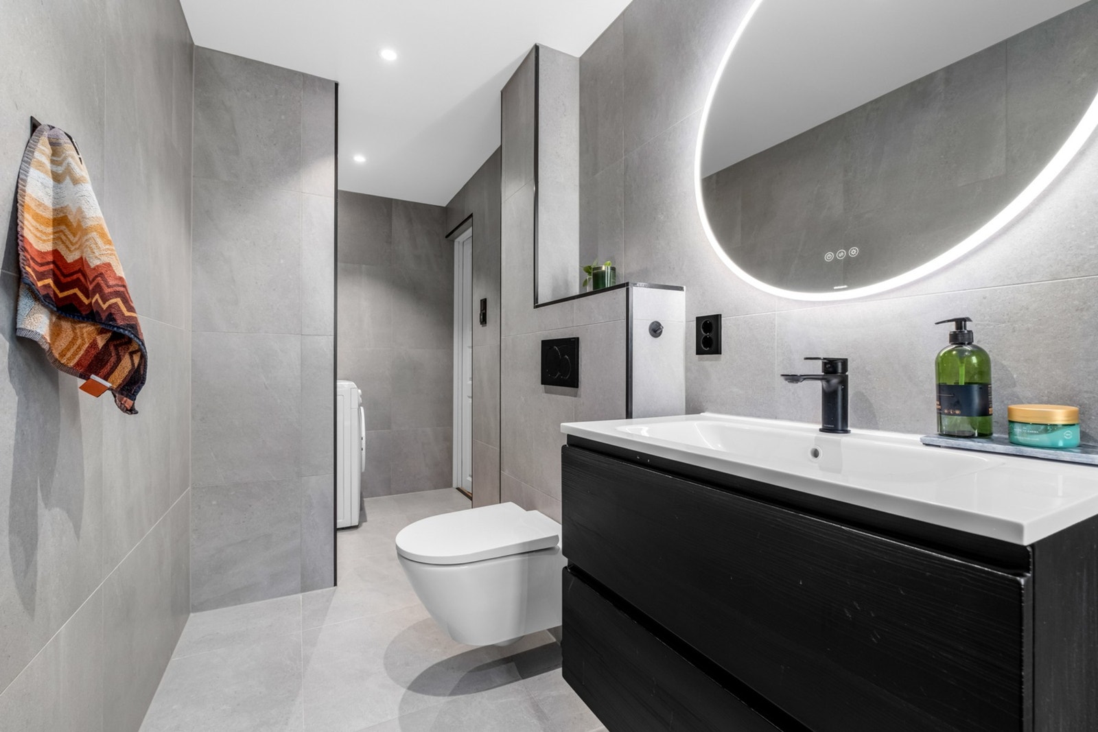 Pent flislagt bad fra 2023 med vegghengt WC, servant, kran og avløp til vaskemaskin og dusjhjørne. Galleribilde