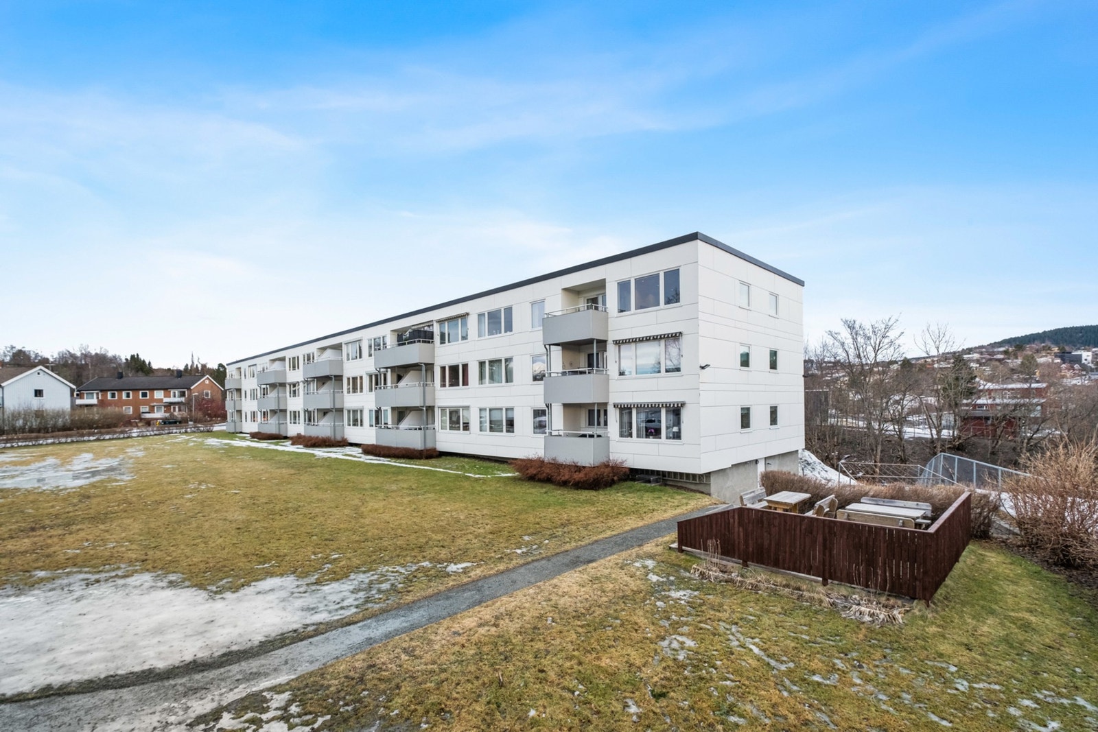 Pent opparbeidet grøntareal utenfor med benker og prydbusker. Galleribilde