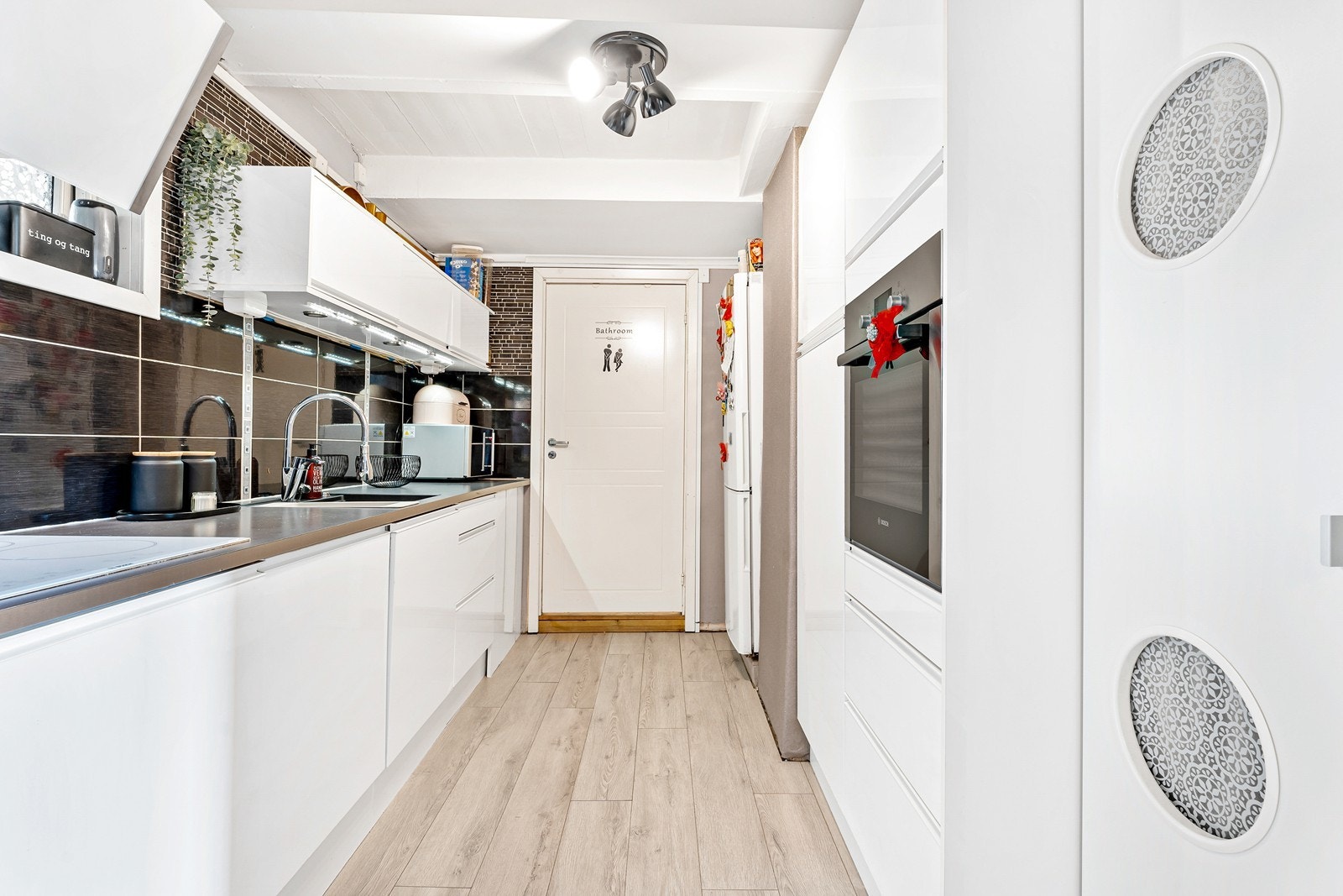 Tidløst og pent kjøkken fra 2015 med hvite, slette fronter og laminat benkeplate. Galleribilde