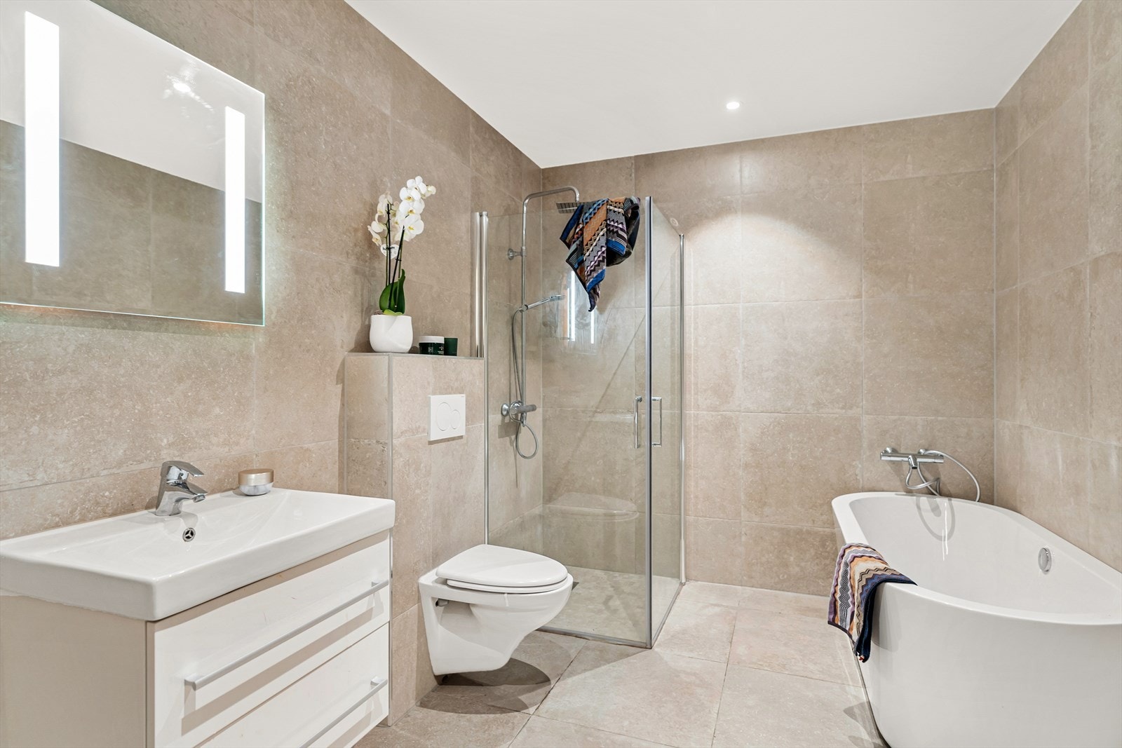 Badet inneholder dusjnisje med glassvegg, vegghengt toalett og helstøpt servant. Her er det også baderomsmøbler med slette fronter, samt speil og lys over servant. Oppgraderte fliser på bad. Galleribilde