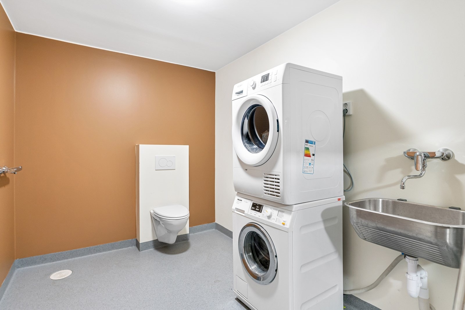 Boligen har også et separat og praktisk bad/vaskerom. Her er det utslagsvask i stål, vegghengt toalett og opplegg for vaskemaskin. Det er lagt opp for dusj på vaskerommet. Galleribilde