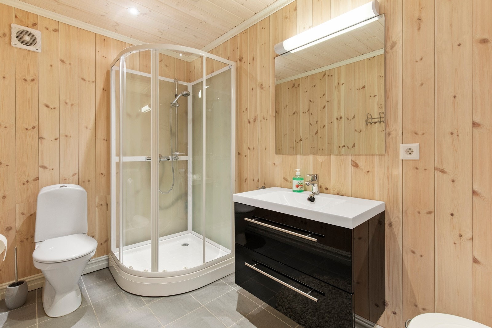 Badet har flislagt gulvoverflate med gulvvarme, samt montert wc, baderomsinnredning, dusjkabinett og opplegg for vaskemaskin Galleribilde