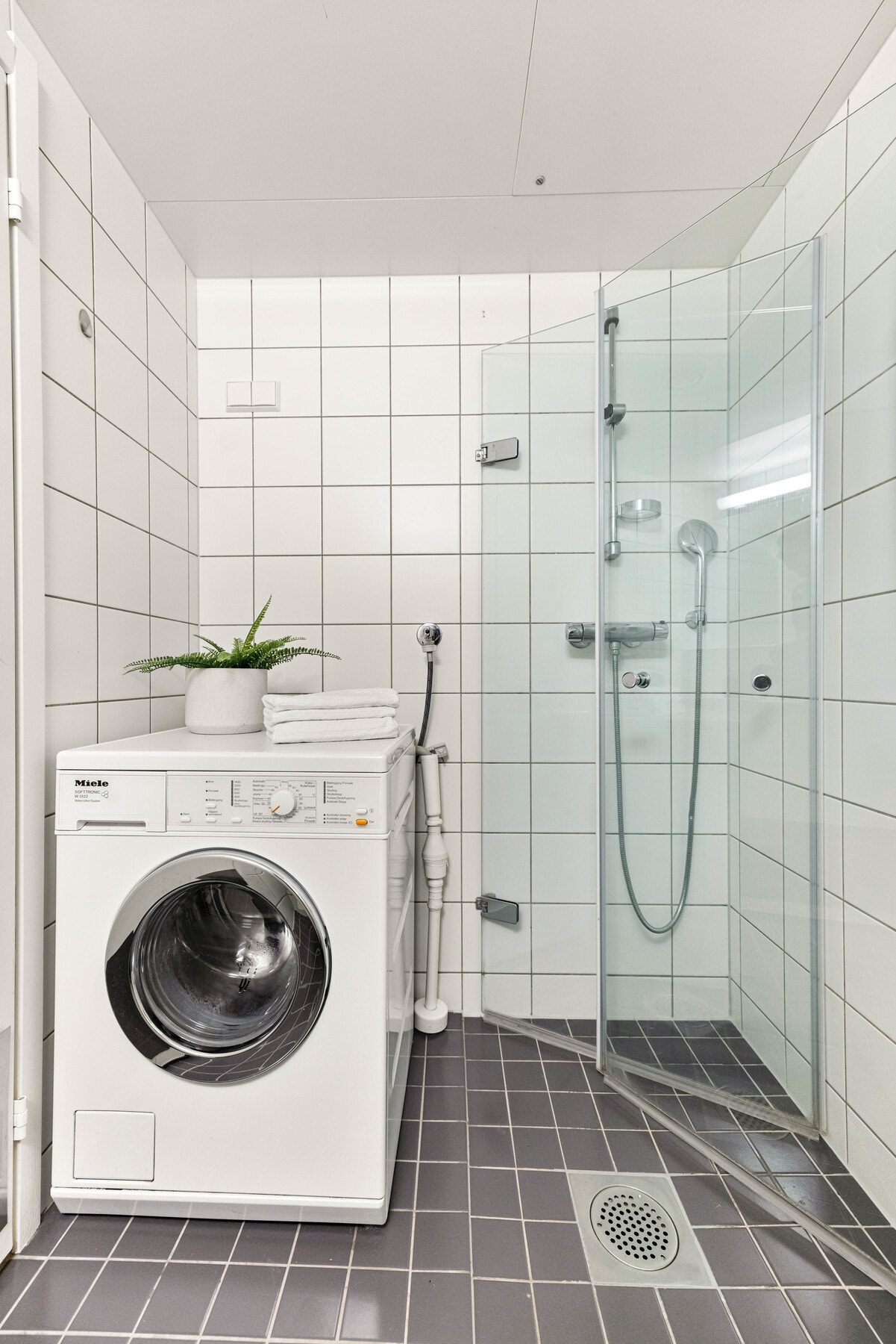 På badet er det opplegg for vaskemaskin og et dusjhjørne med plassbesparende dører i herdet glass. Galleribilde
