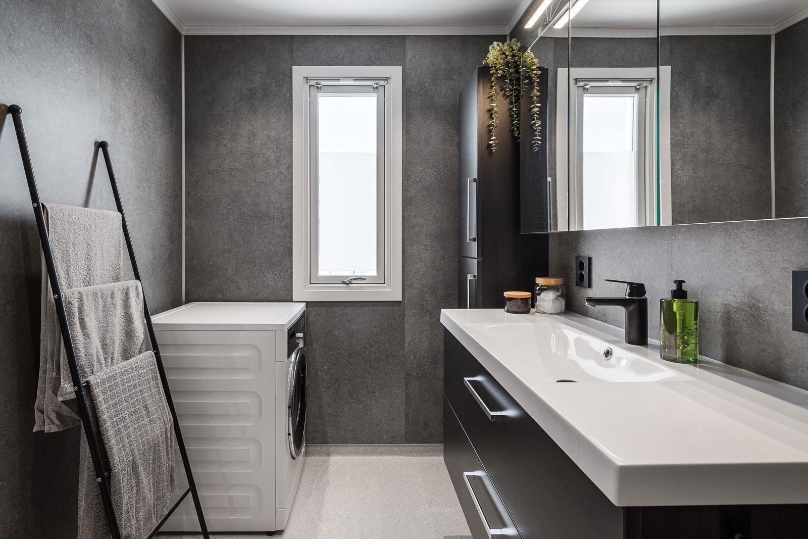 Badet har innredning med skuffer og heldekkende servant, veggskap og speilskap over servanten. Det er opplegg for vaskemaskin og tørketrommel. Galleribilde