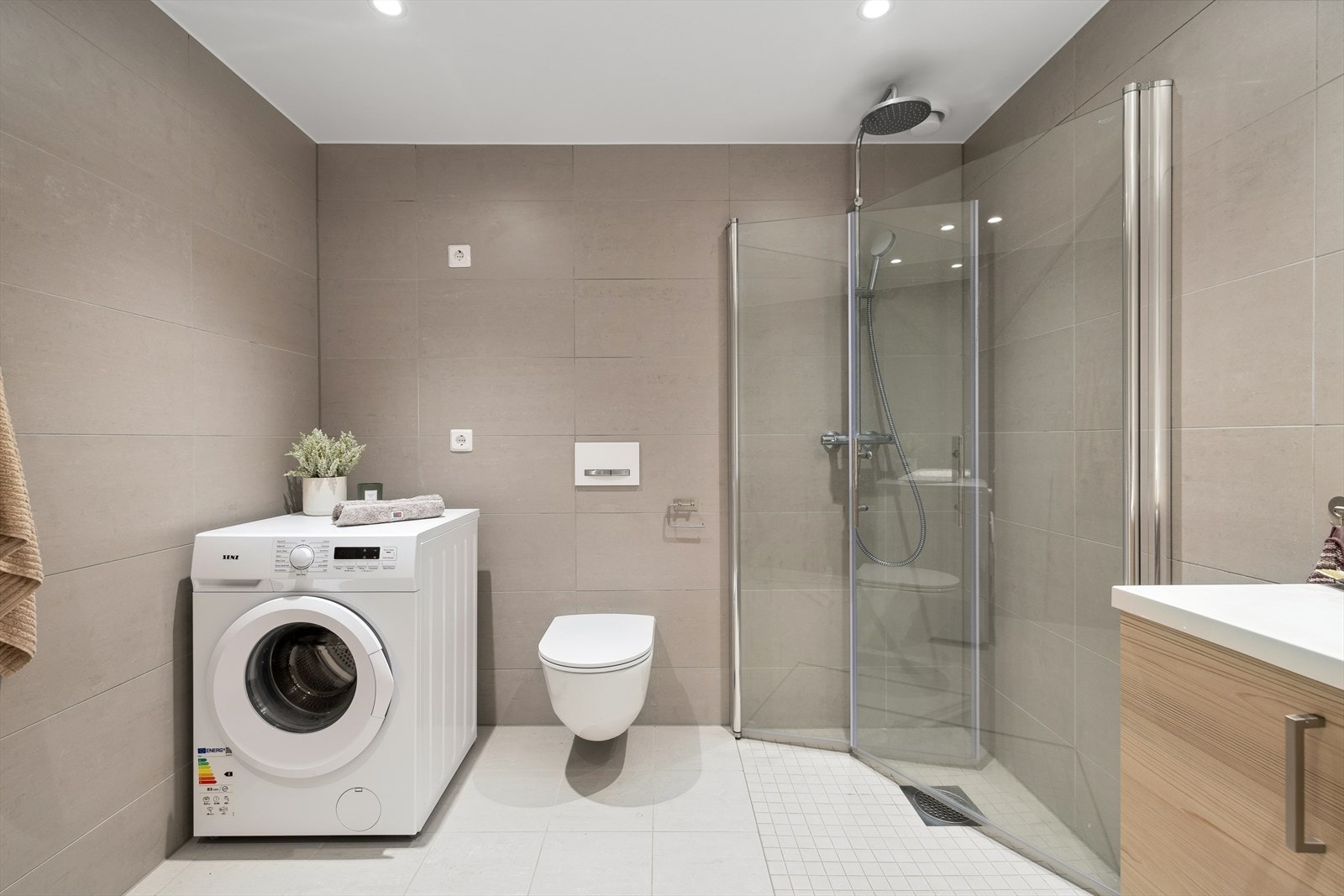 Lekkert lyst fliselagt bad med fliser på vegger og gulv. Galleribilde