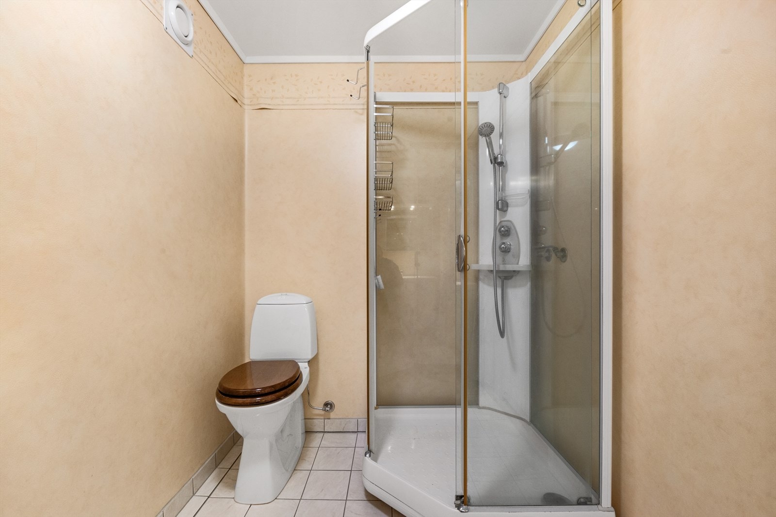 Badet har dusjkabinett, gulvmontert toalett, og skap under servant. Galleribilde