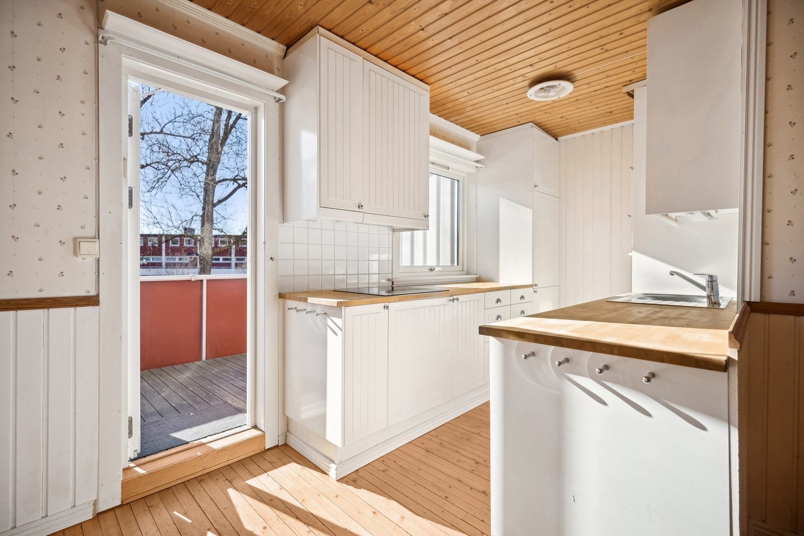 Eldre kjøkkeninnredning med profilerte fronter. Innredningen består av heltre benkeplate med nedfelt kum i rustfritt stål, kullfilterventilator og opplegg for oppvaskmaskin. Galleribilde