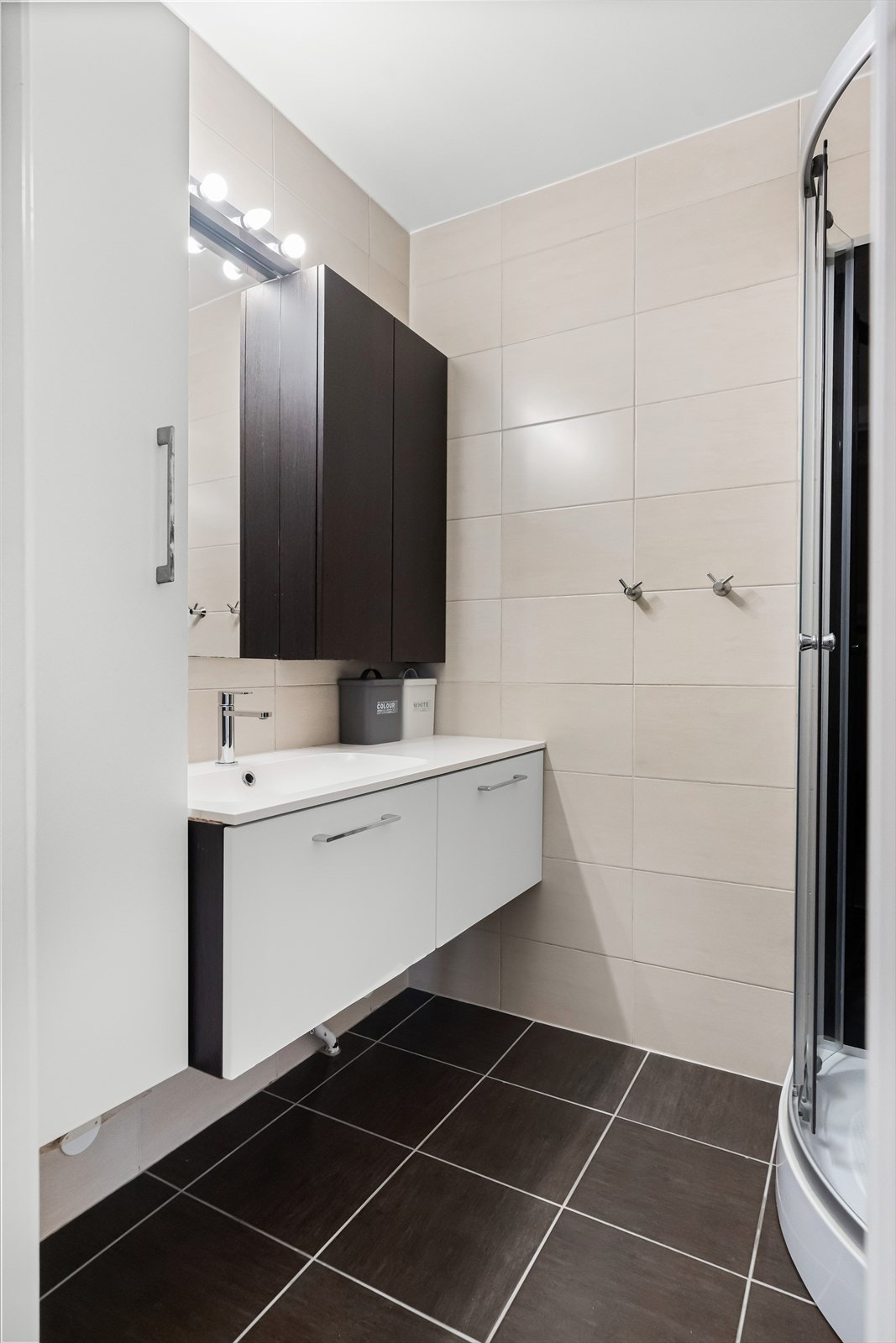 Videre er rommet innredet med servantskap, nedfelt servant, underskuff og 1-greps blandebatteri, høyskap, dusjkabinett og opplegg for vaskemaskin. Galleribilde