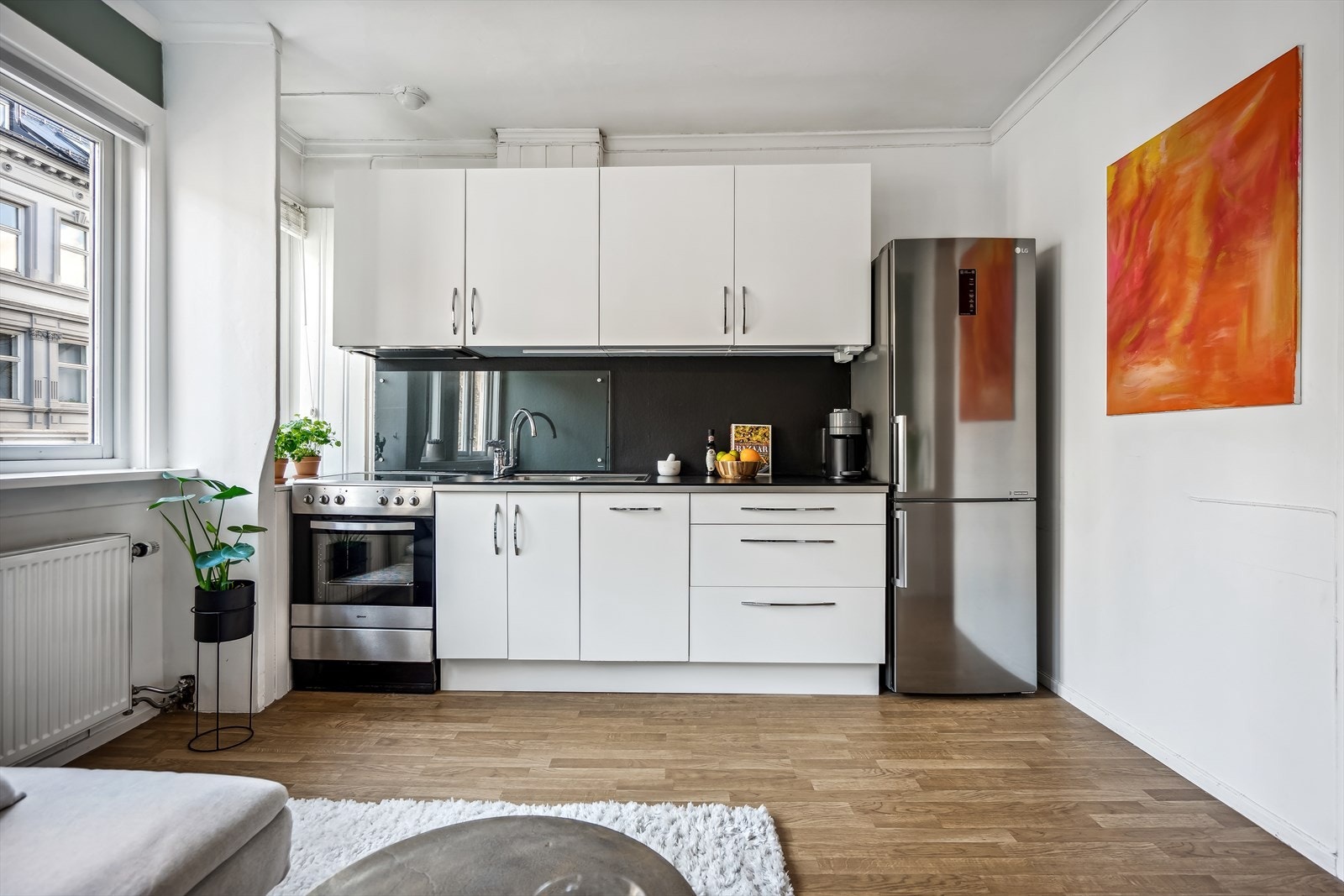 Innredningen består av hvite matte fronter, benkeplater i laminat, rustfri oppvaskkum med avrenningsplate, ventilator med kullfilter og integrert oppvaskmaskin. Galleribilde