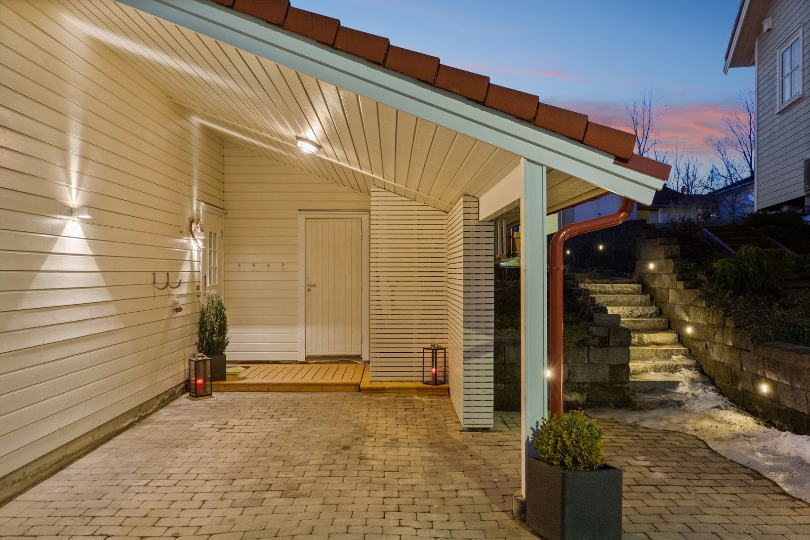 Det er parkering i og utenfor en steinlagt carport, med videre adkomst til en isolert bod på ca. 11 kvm. Galleribilde