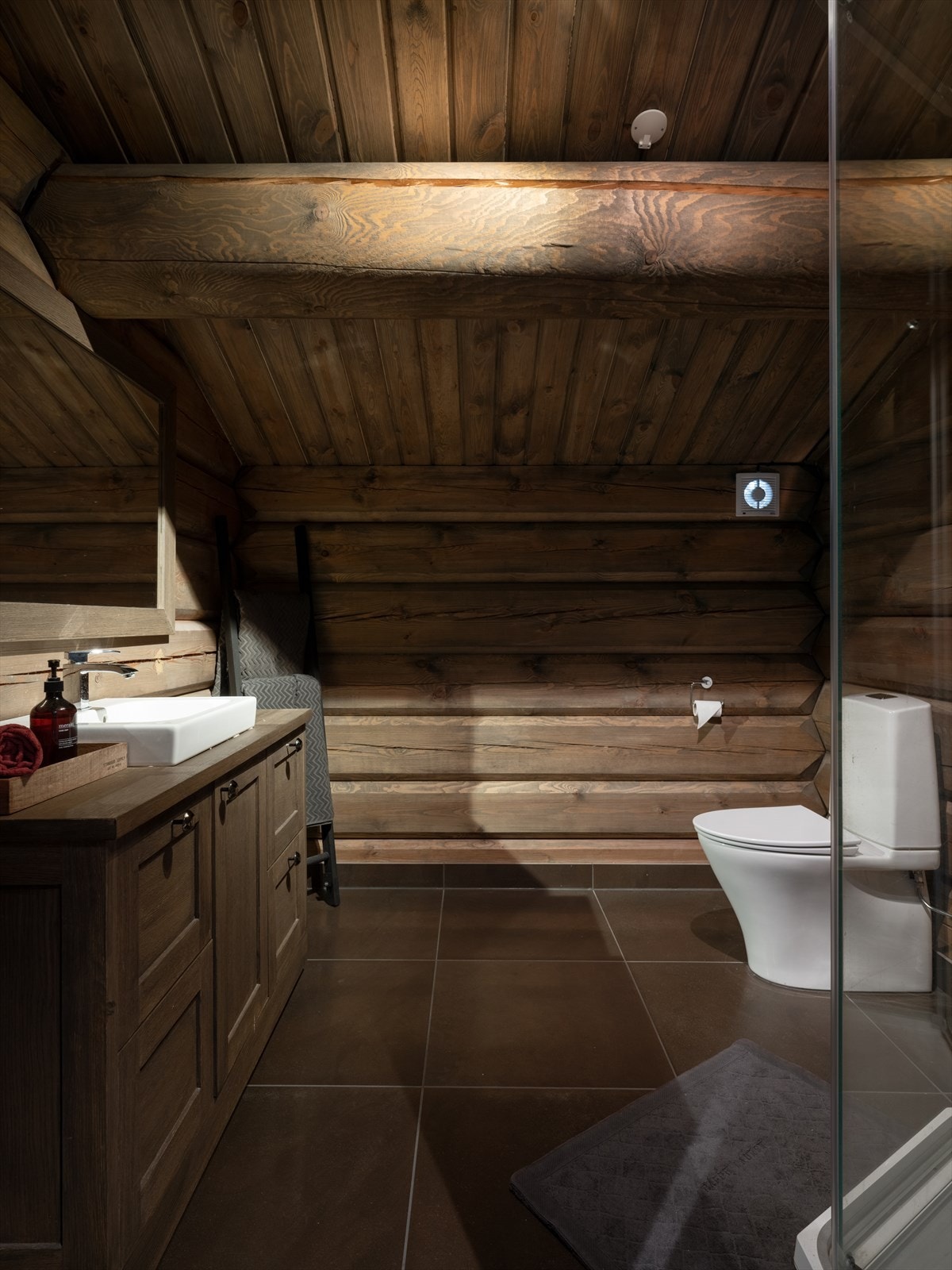 Badet i loftetasjen har en lun og behagelig atmosfære som inneholder servantseksjon med skap og skuffer, speil, servant, wc og dusjkabinett. Galleribilde