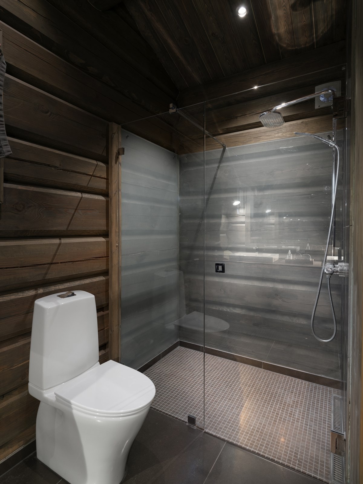 Badet har store delikate fliser på gulvet med termostatstyrt varme, samt behandlet tømmer, panel og fliser på veggene. Galleribilde