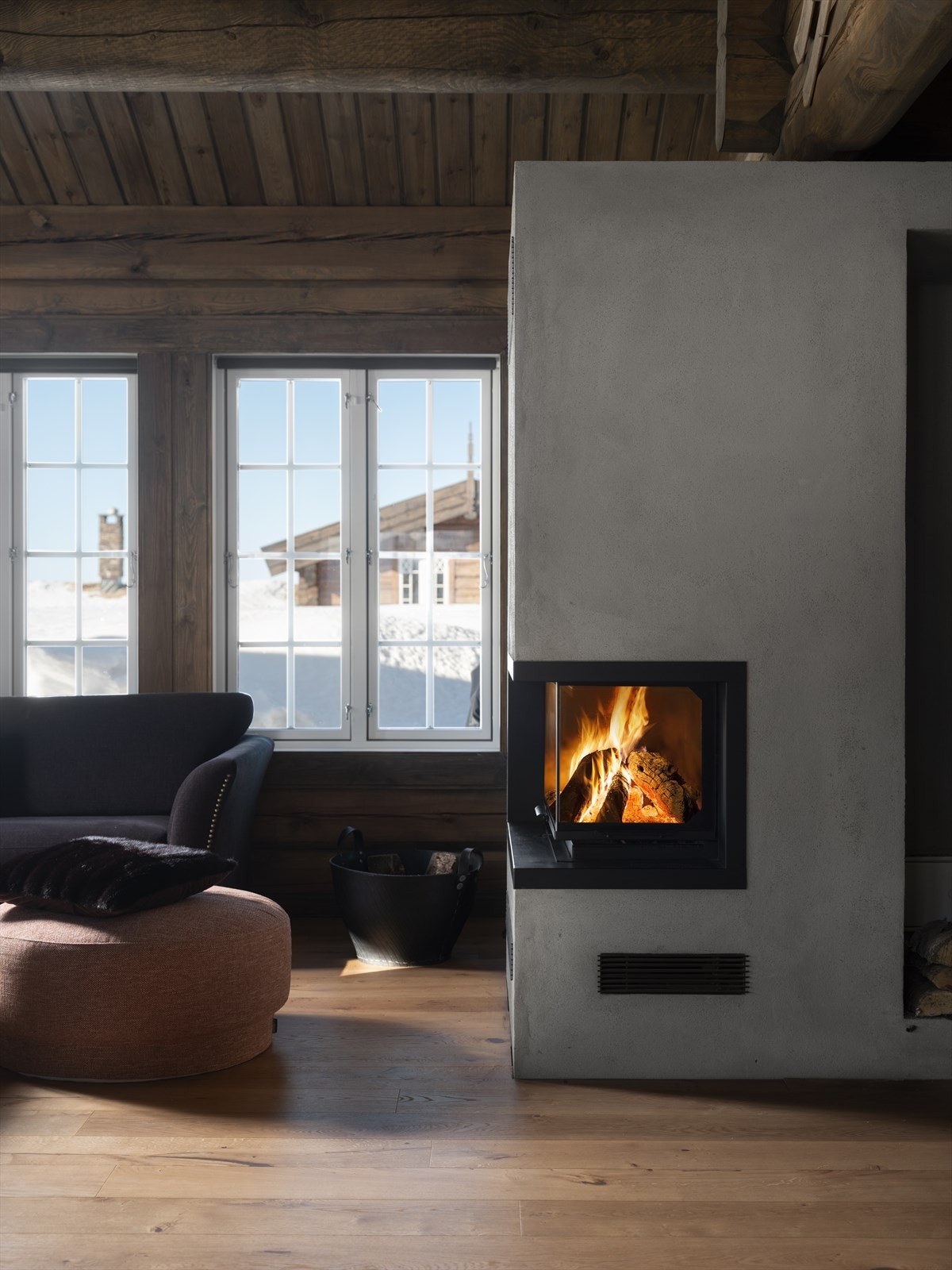 Mellom stua og kjøkkenet er rommets midtpunkt, en flott, lukket peis som varmer godt på kalde dager og skaper den gode hyttefølelsen. Galleribilde