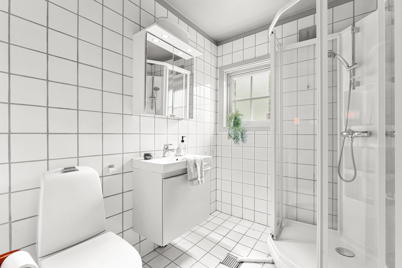 Badet i første etasje er flislagt, og har gulvstående toalett, servantinnredning med underskap og dusjkabinett. Galleribilde