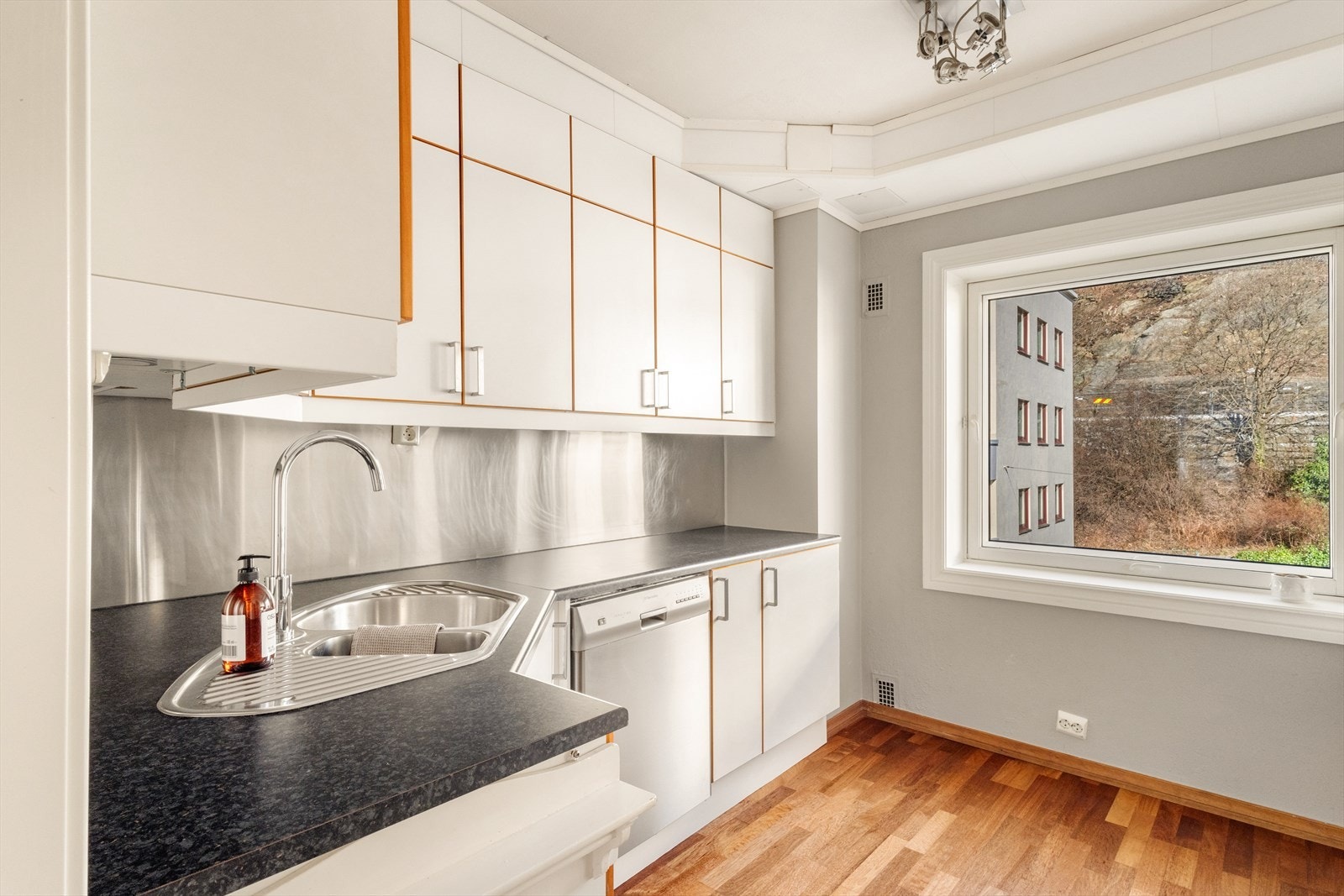 Kjøkkeninnredning med slette fronter, laminat benkeplate, over benkeplaten er det montert plate, stål oppvaskkum,
ventilator. Opplegg for oppvaskmaskin. Galleribilde