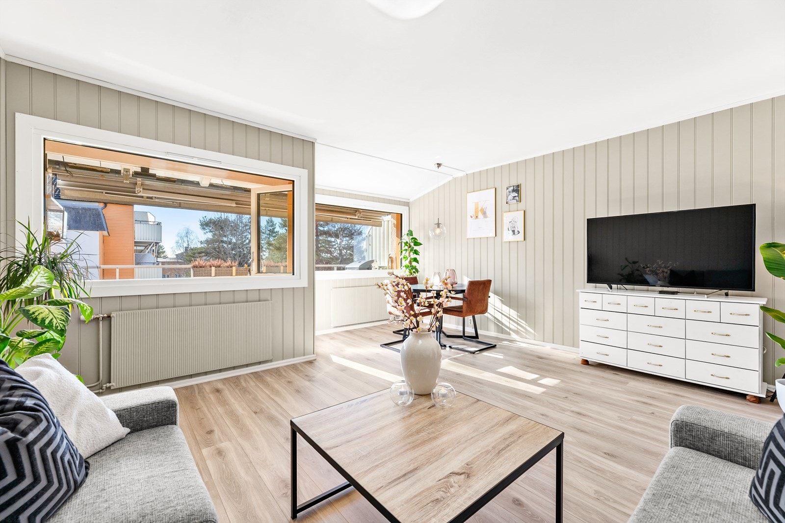 Romslig stue med plass til både sofagruppe, et lite spisebord og annet møblement Galleribilde