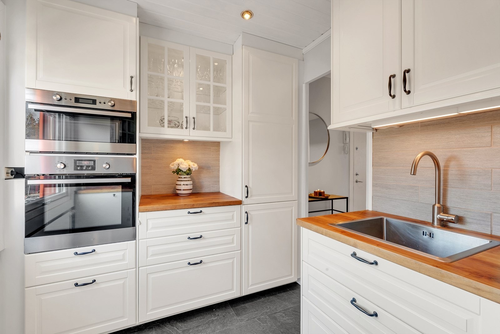 Kjøkken med laminat på gulv, malte slette vegger og malt panel i tak med downlights. Alt av hvitevarer er integrert. Galleribilde