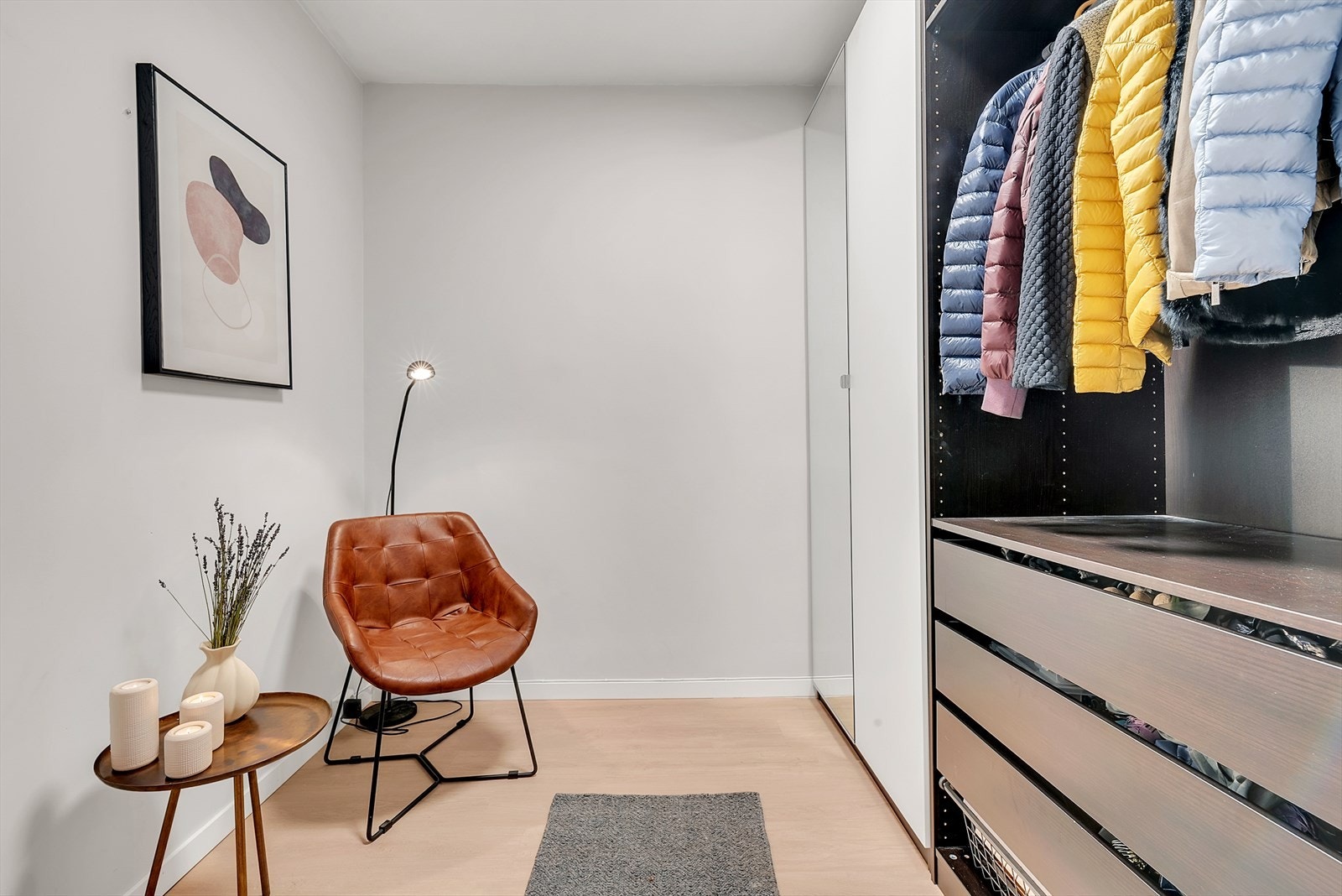 Omkledningsrom med laminat på gulv, malte slette vegger og malt tak. Her er det montert et garderobeskap samt skapinnredning med hyller og oppheng. Galleribilde