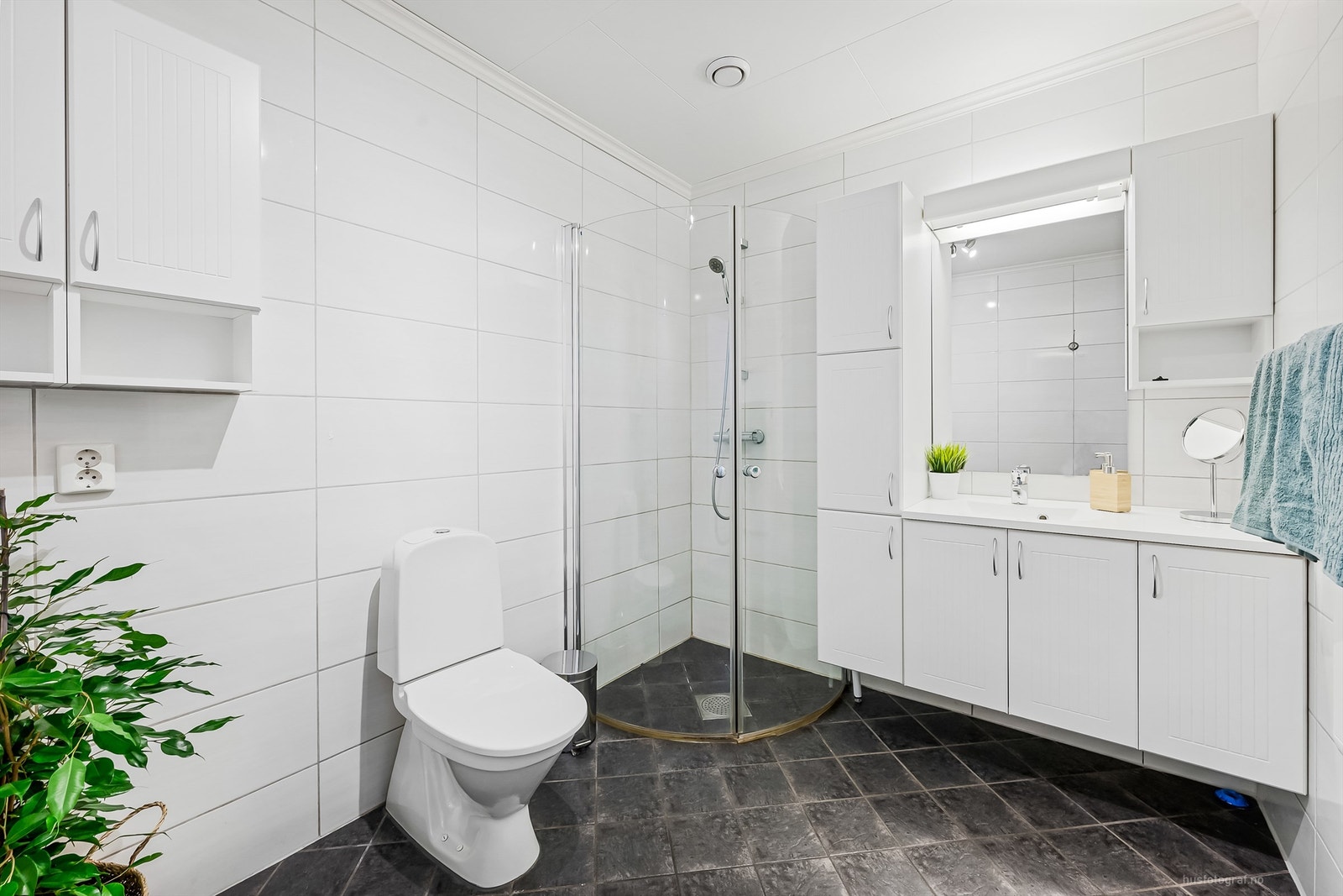 Badet har dusjhjørne med foldedører av glass Galleribilde