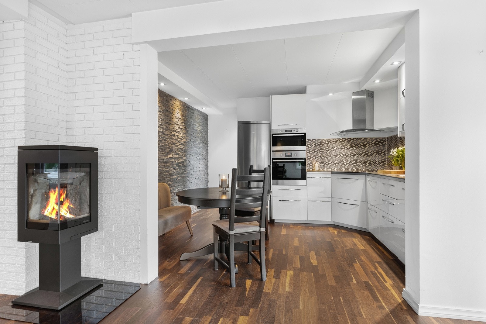 Kjøkkenet ligger innenfor stuen, med god kontakt via bred åpning, og parketten er lagt sømløst mellom rommene. Galleribilde