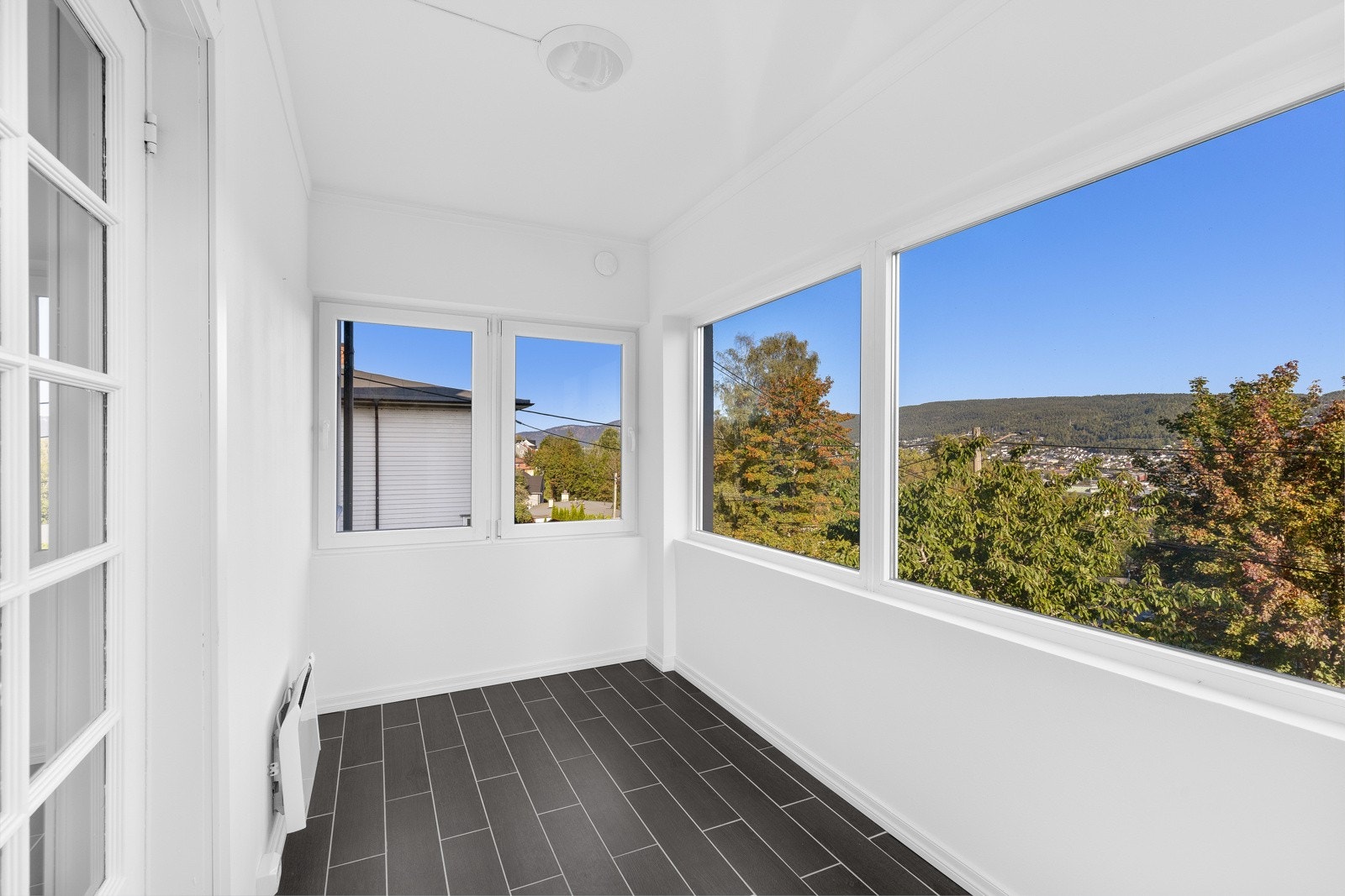 Vinterhagen har flislagt gulv, hvitmalte overflater og store vinduer rundt hele. Galleribilde