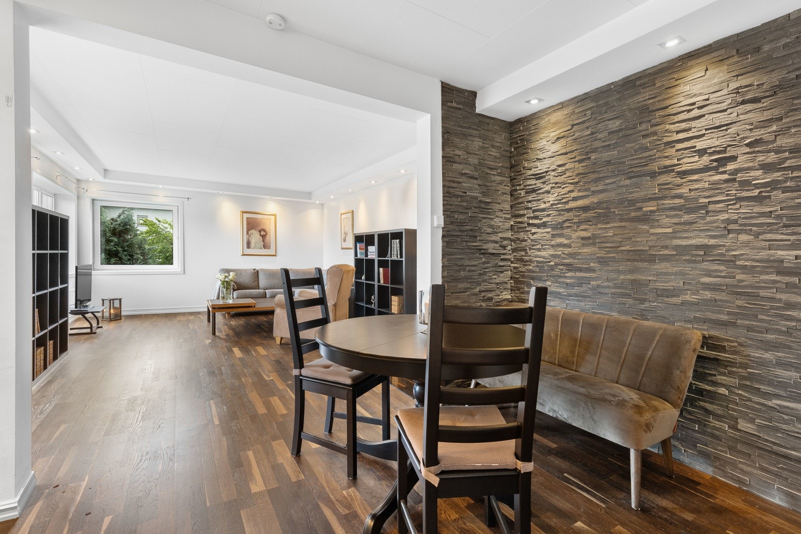 Leiligheten har en tiltalende stue med hjørnevinduer og hvitmalte, glatte vegger Galleribilde