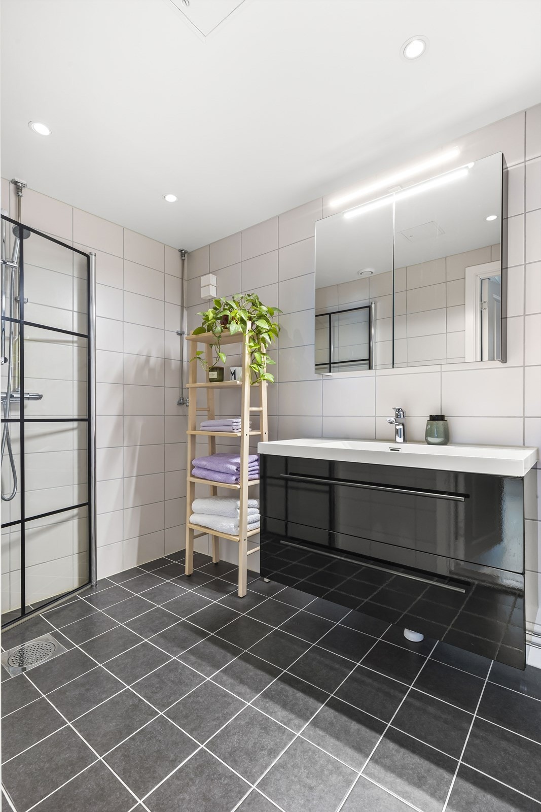 Badet er innredet med servant med skuffer og dusjnisje med innfellbare glassdører. Speilskap og belysning i overkant av servant, varmekabler i gulv og opplegg for vaskemaskin. Galleribilde