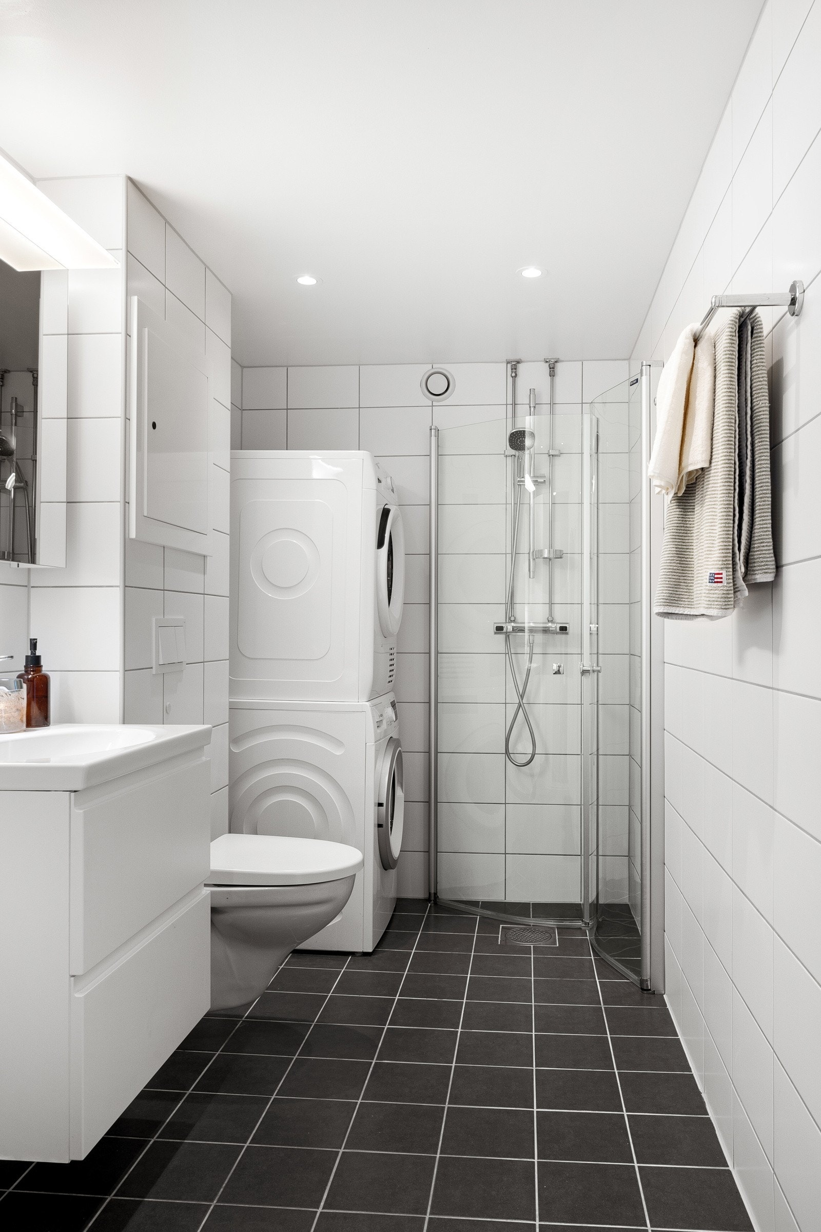 Badet har grå fliser på gulv, hvite fliser på veggene, gulvvarme og downlights. Her er det lett å sette sitt eget preg. Galleribilde