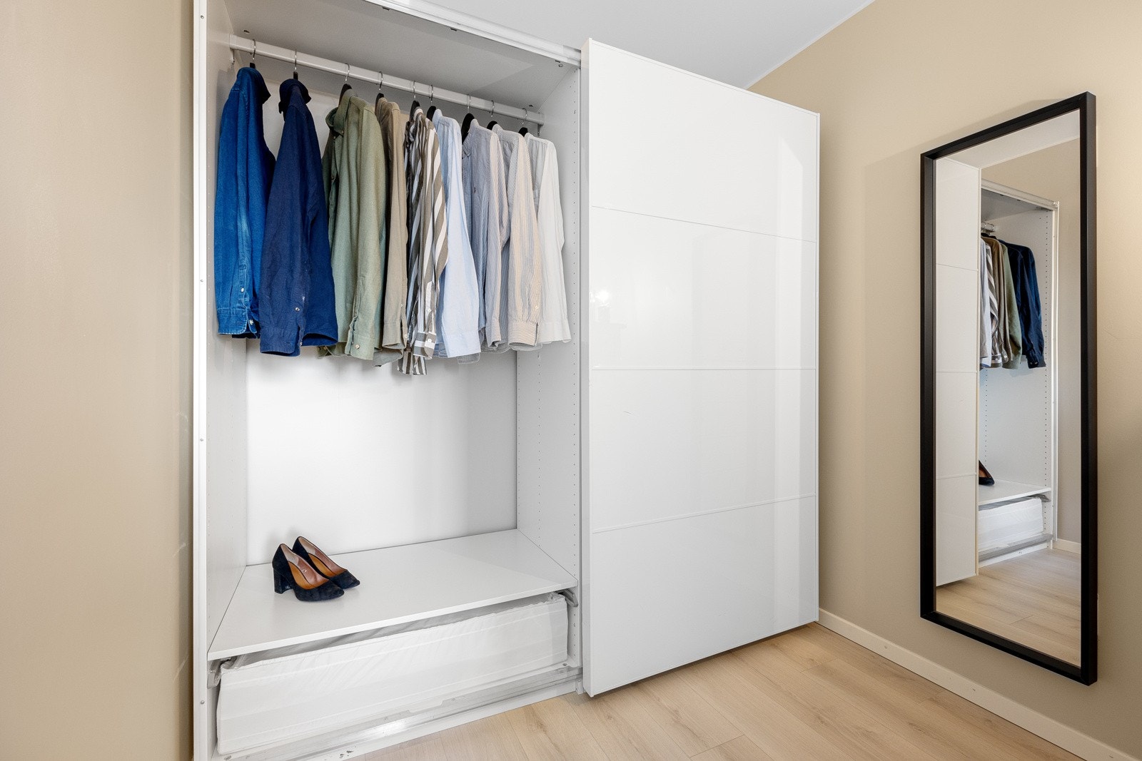 Det er god plass til tøy og sko i en stor skyvedørsgarderobe med hvit høyglansfront. Galleribilde