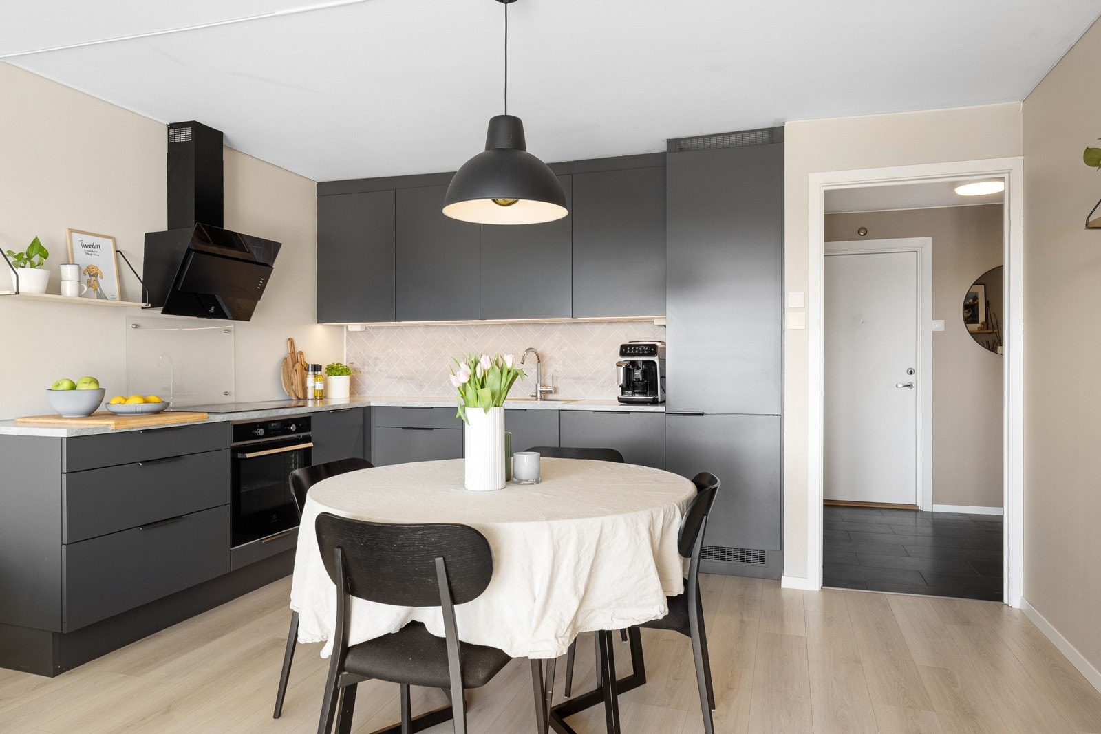 Kjøkkenet har glatte, grå fronter, sorte håndtak og benkeplate i lys laminat. Det er god plass til spisebord mot stuen. Galleribilde