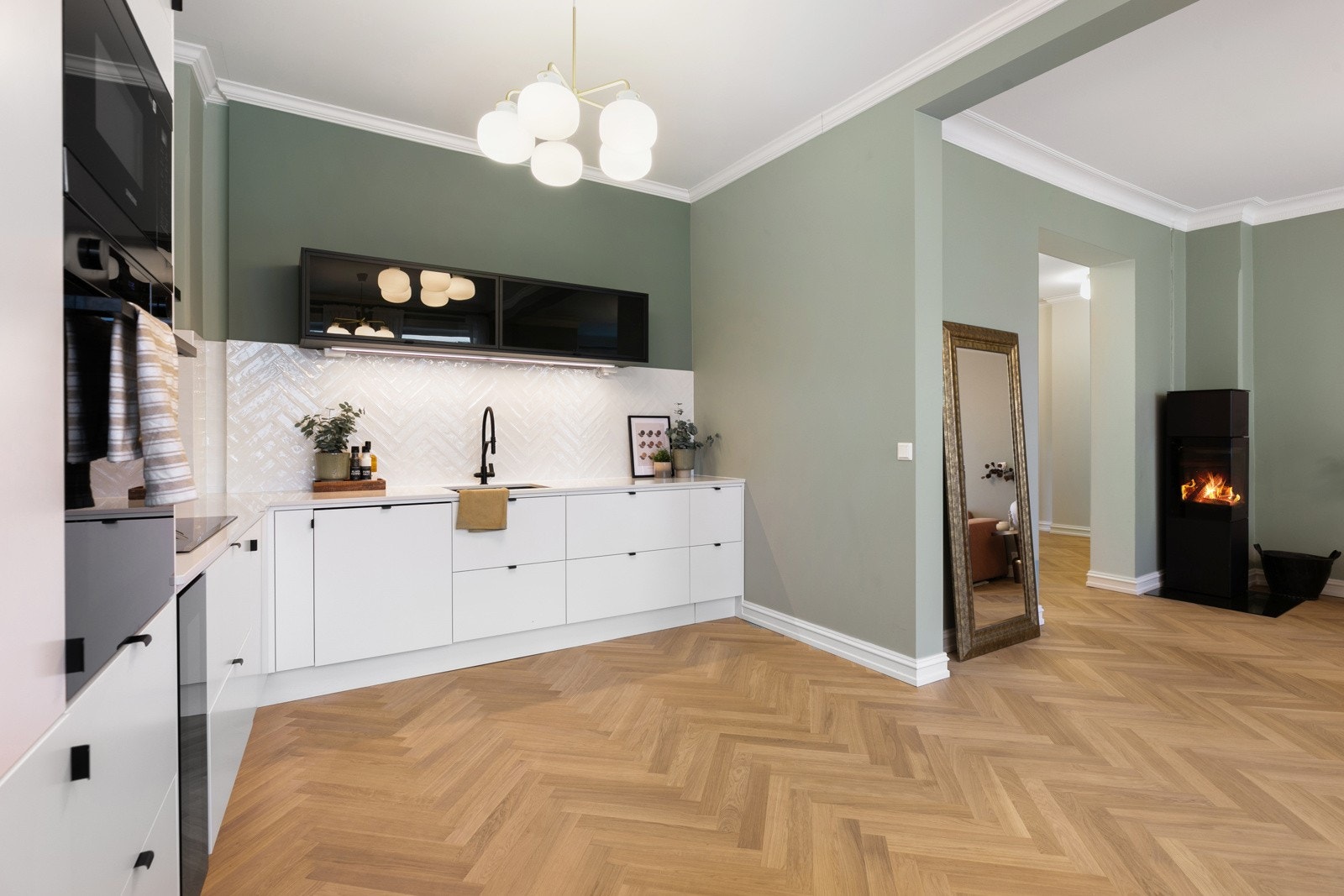 Tidsriktig kjøkkeninnredningen fra med hvite slette fronter og fiskebensfliser på vegger. Integrerte hvitevarer oppvaskmaskin, kjøl/frys, stekeovn og micro i høyskap samt veggmontert avtrekksvifte og vinkjøleskap medfølger Galleribilde