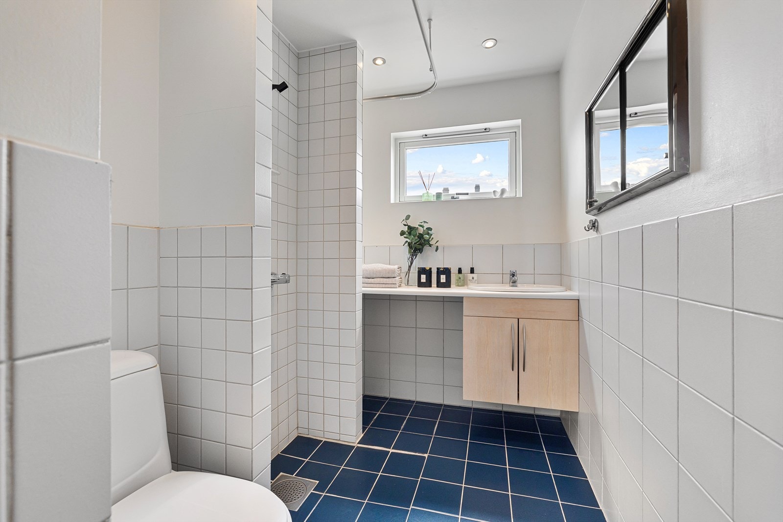 Pent fliselagt bad med varme i gulv og downlights i himling. Badet er innredet med wc, dusj og servant i glatt servantskap. Galleribilde