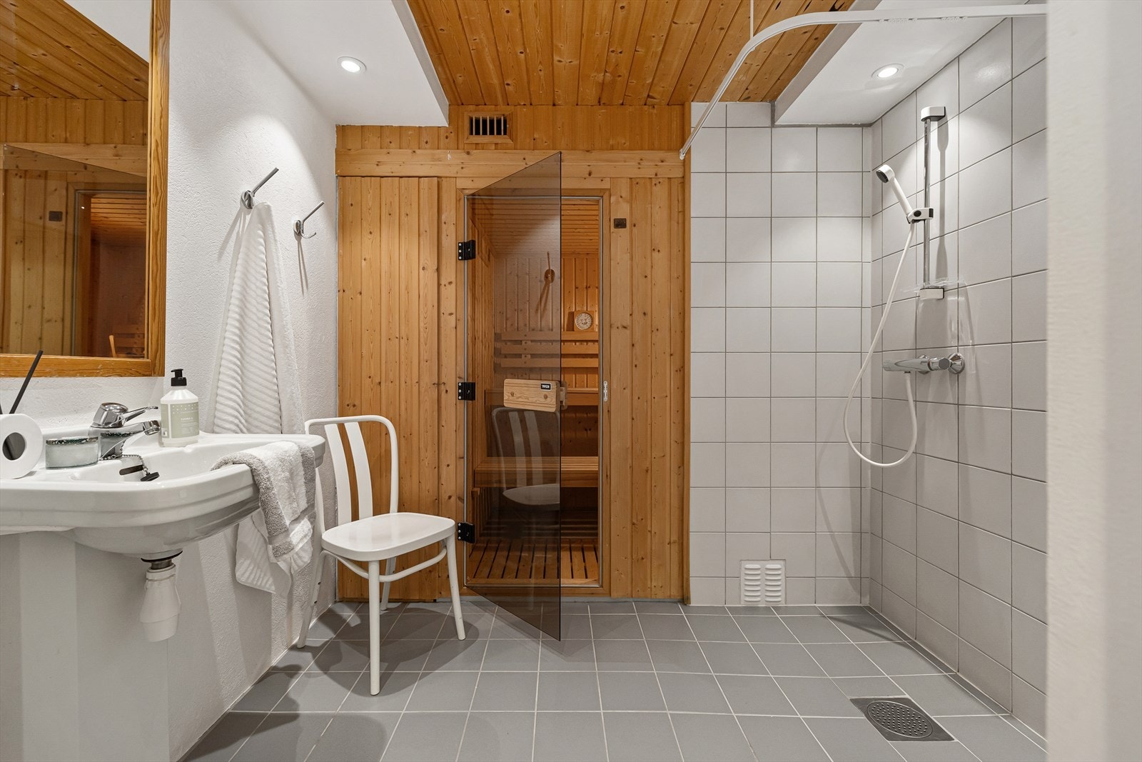 Lyst og fliselagt bad med varmekabler i gulv. Badet er innredet med dusj, wc og servant. Galleribilde