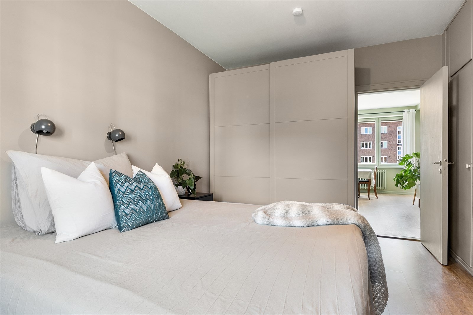 Veggene er malt i en behagelig beigetone som bidrar til en god natts søvn. Langs den ene kortveggen er det plassert et stort garderobeskap for klær og sko. Galleribilde