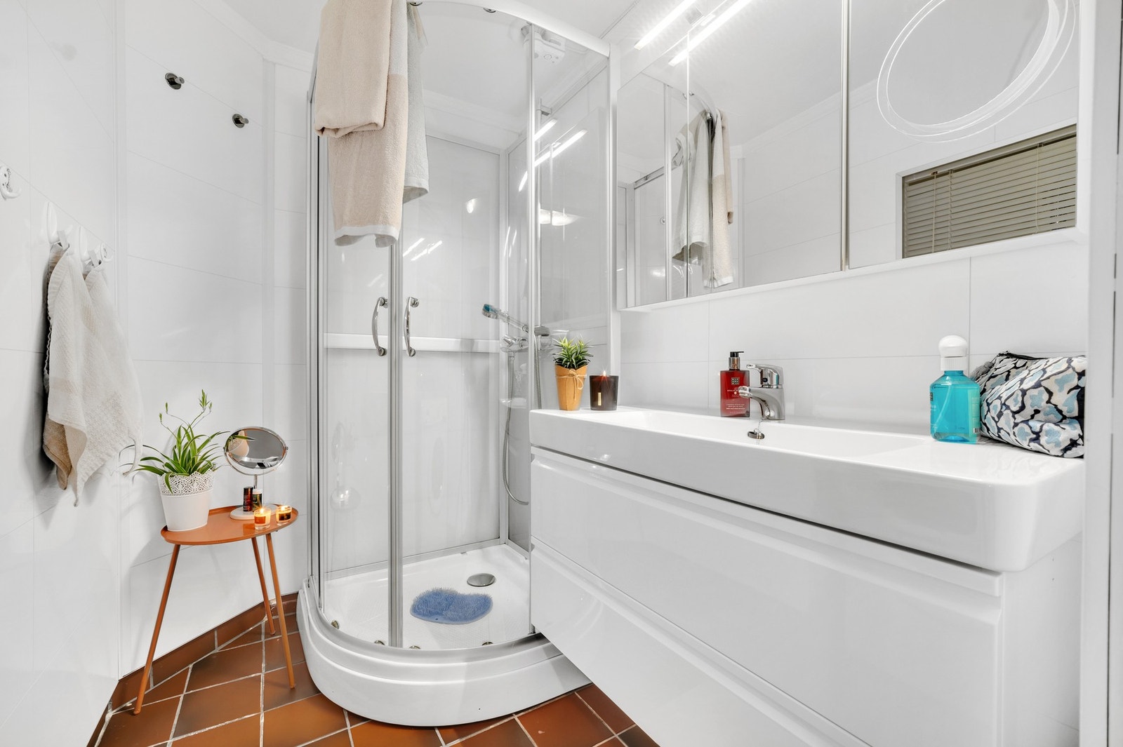 Badet har flis på gulv og vegg, dusjkabinett, servant med underskap samt opplegg for vaskemaskin. Galleribilde