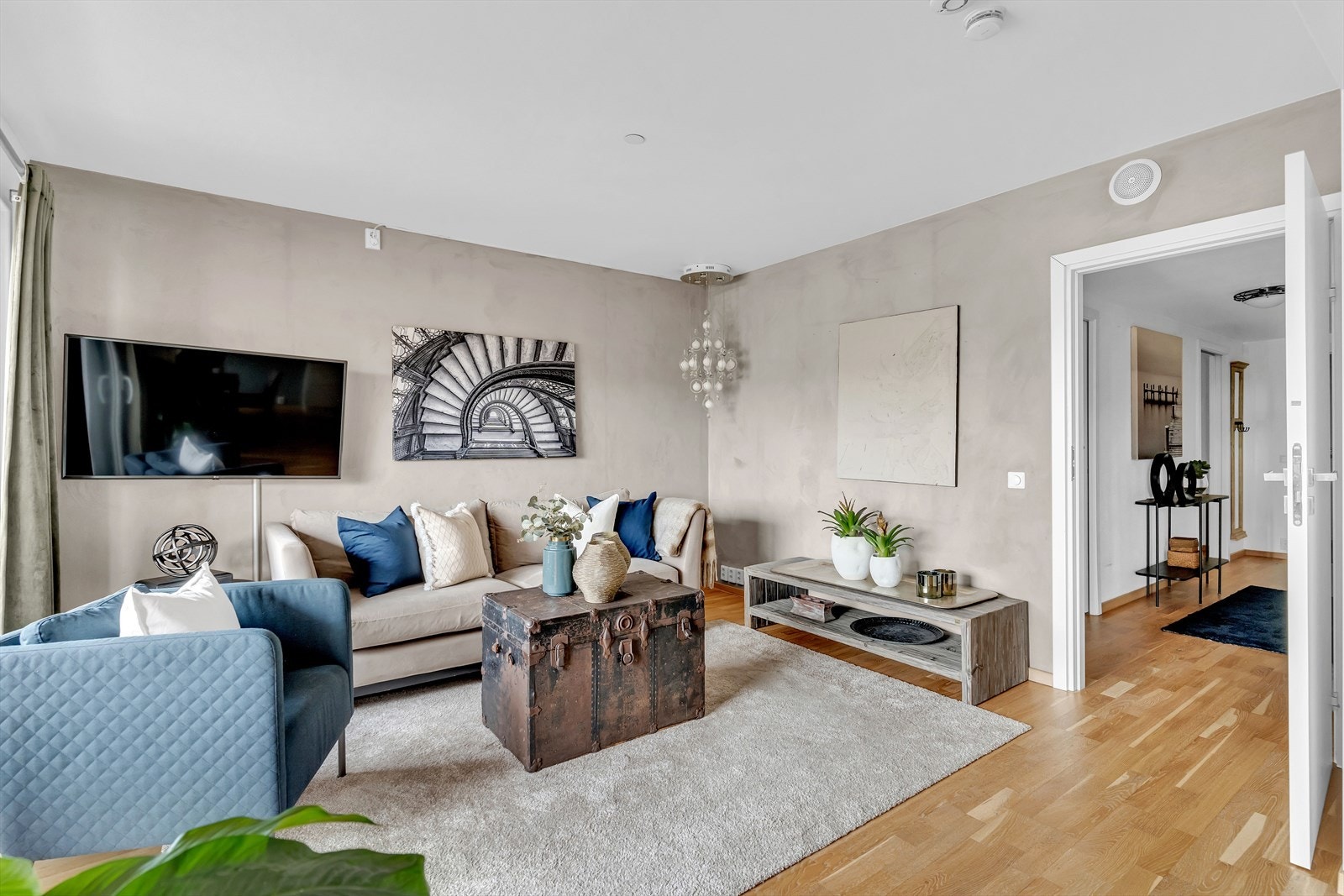 Her har man god plass til sofa og tv-møblement, og veggene er malt hvite og beige som står til stil med resten av rommet. Galleribilde