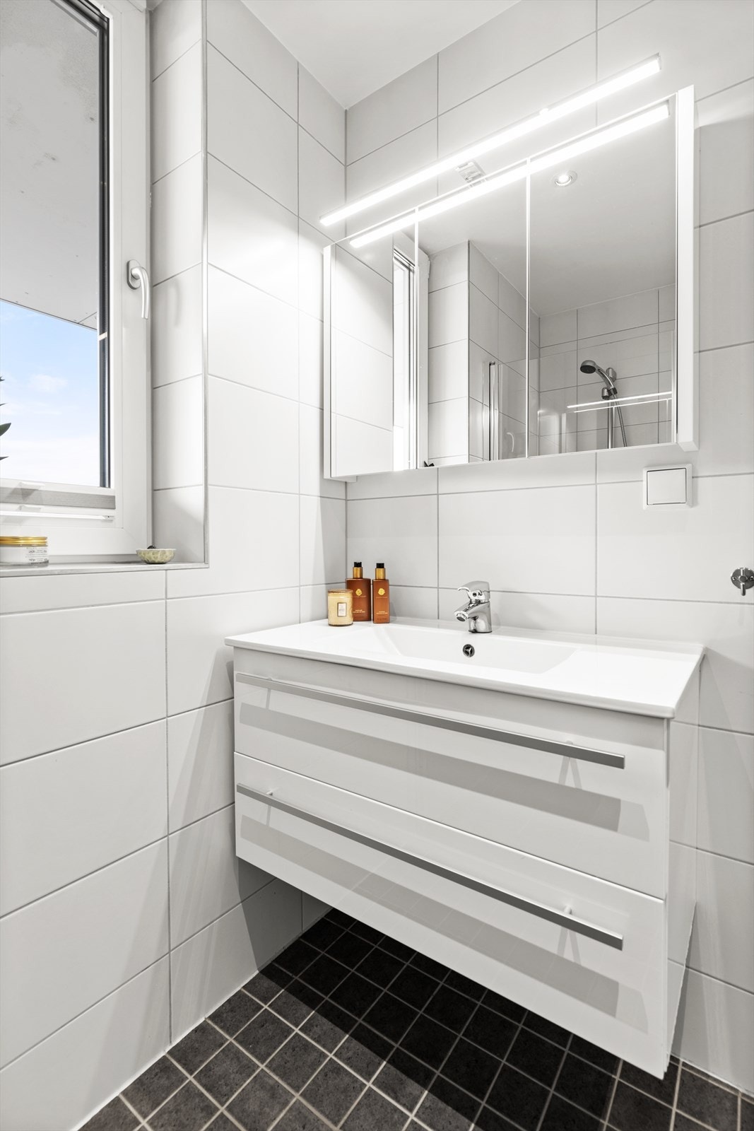Lys og lekker servant på badet som passer perfekt til de lyse flisene på veggen i kontrast til de mørkere flisene på gulvet. Galleribilde