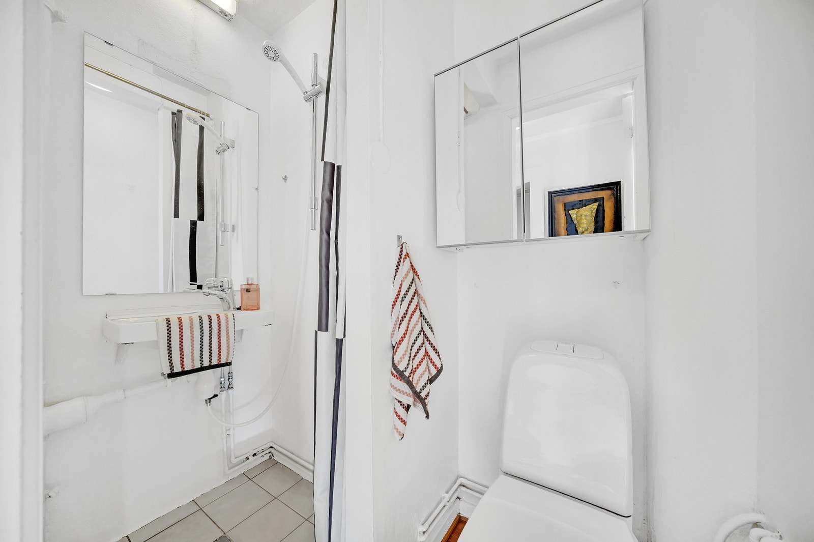 Lyst baderom som er innredet med WC, dusjsone og vegghengt servant. Galleribilde