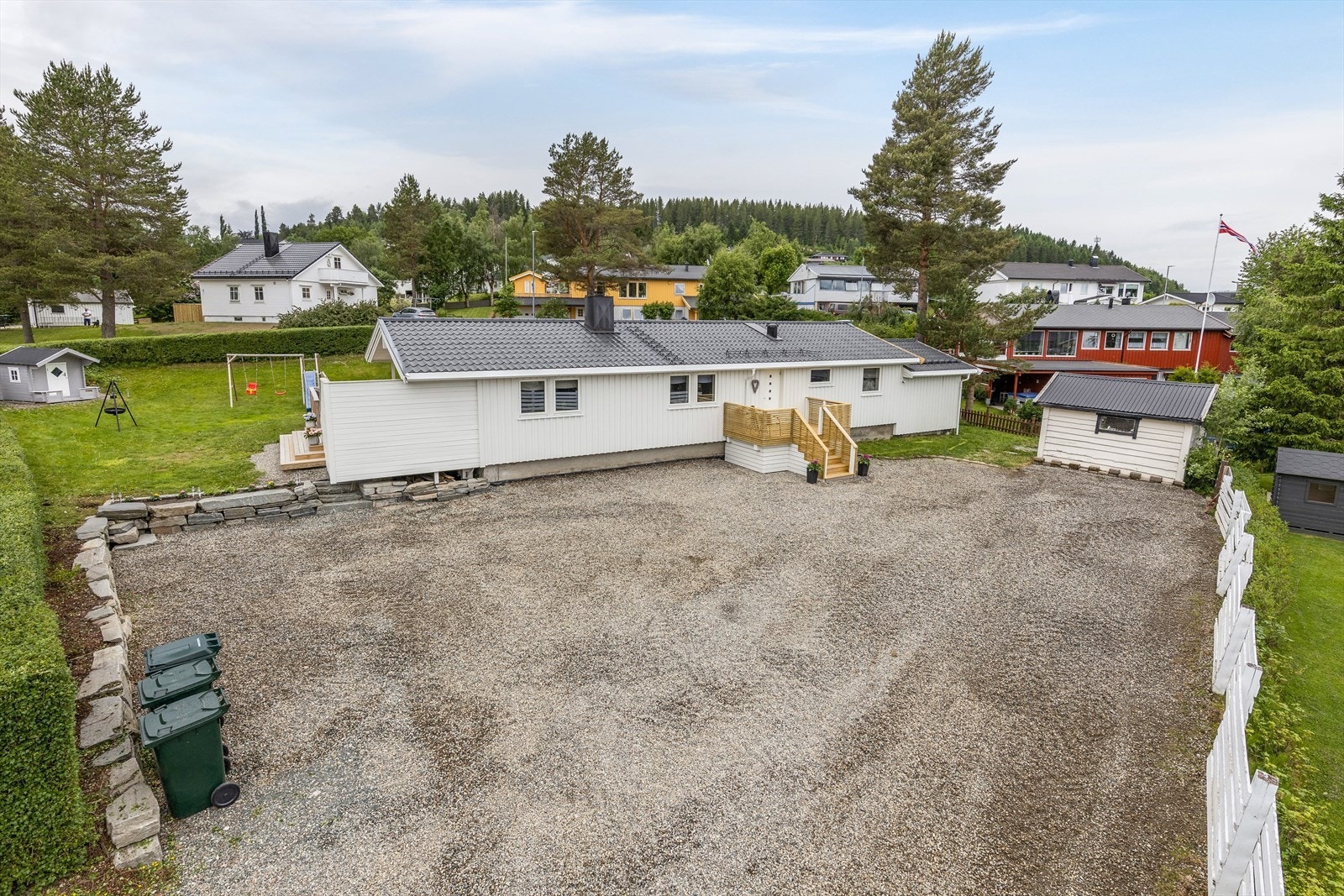 Det er plass til flere biler på gruslagt gårdsplass, og i 2023 ble det montert elbillader. Galleribilde