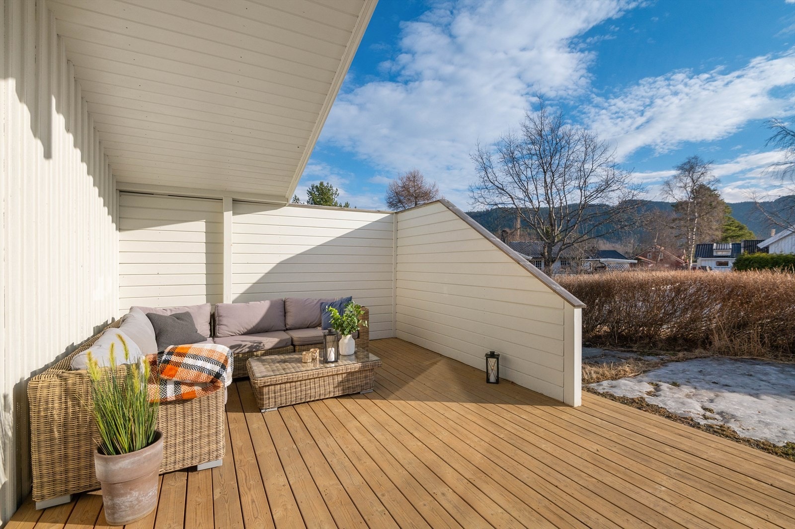 To høye levegger på den ene siden av terrassen danner en koselig, skjermet krok til sofagruppen. Galleribilde