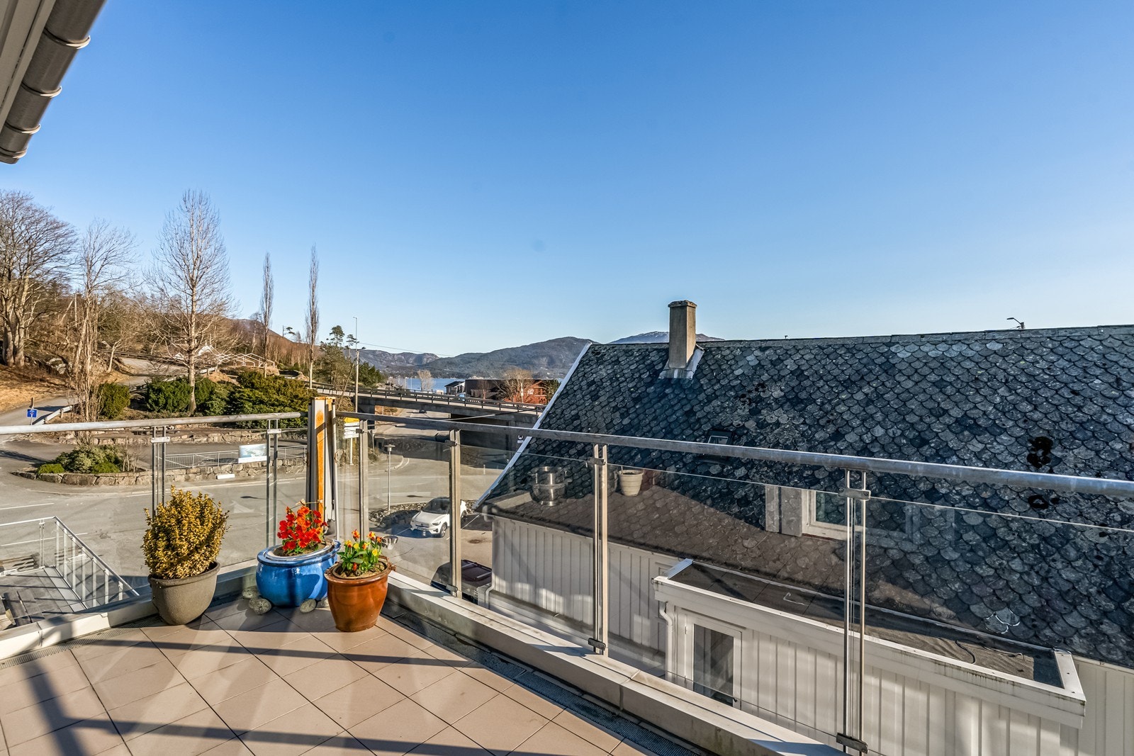 Utgang til stor og delvis overbygget terrasse med glassrekkverk. Galleribilde