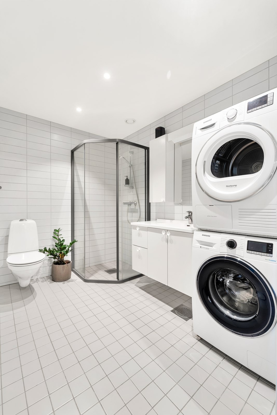 Badet er utstyrt med vegghengt wc, dusjhjørne med glassdører, servant med over- og underskap, samt opplegg for vaskemaskin og tørketrommel. Galleribilde