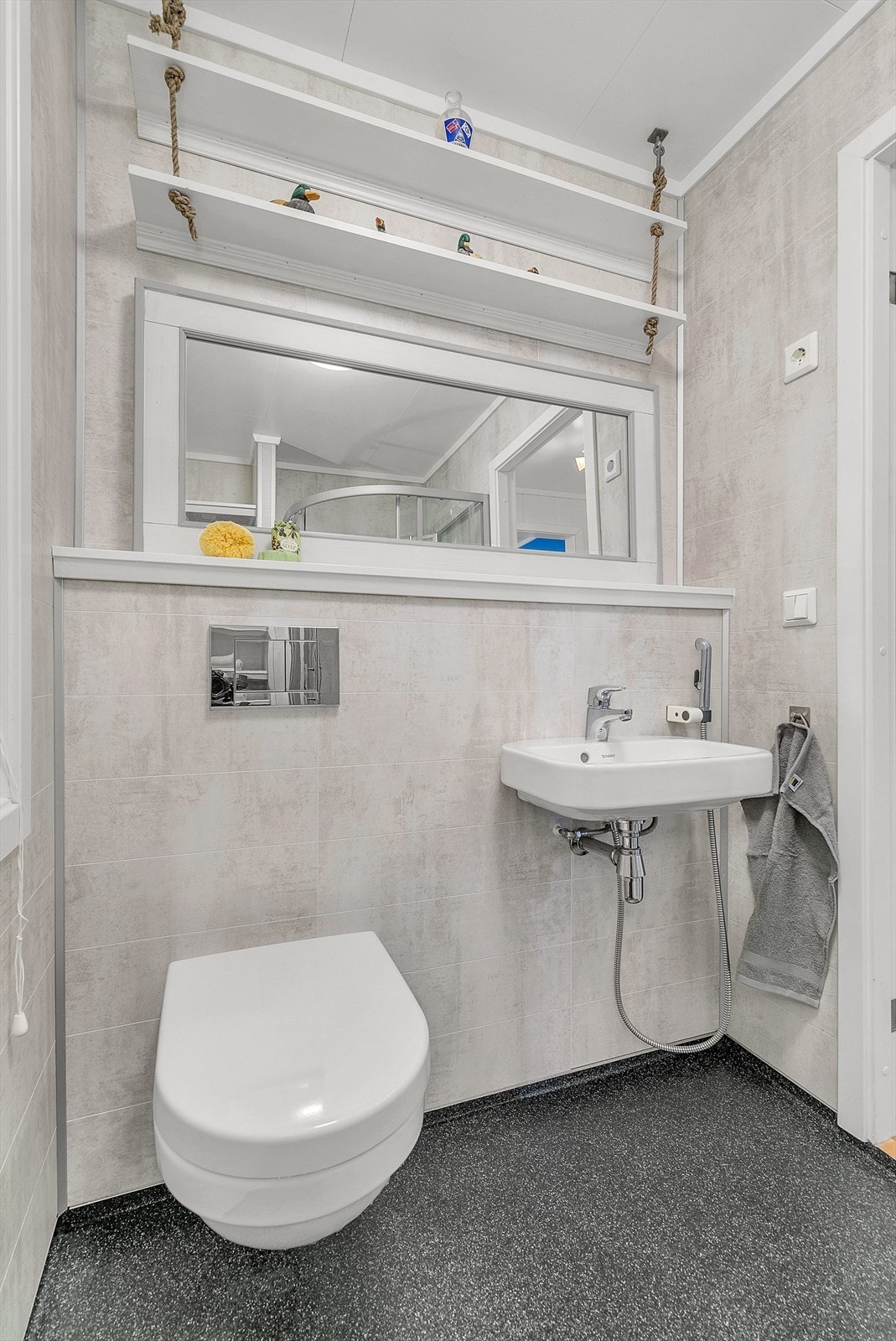 Vegghengt toalett, servant og dusjkabinett på bad. God plass for oppbevaring av baderomsartikler i hyller. Galleribilde