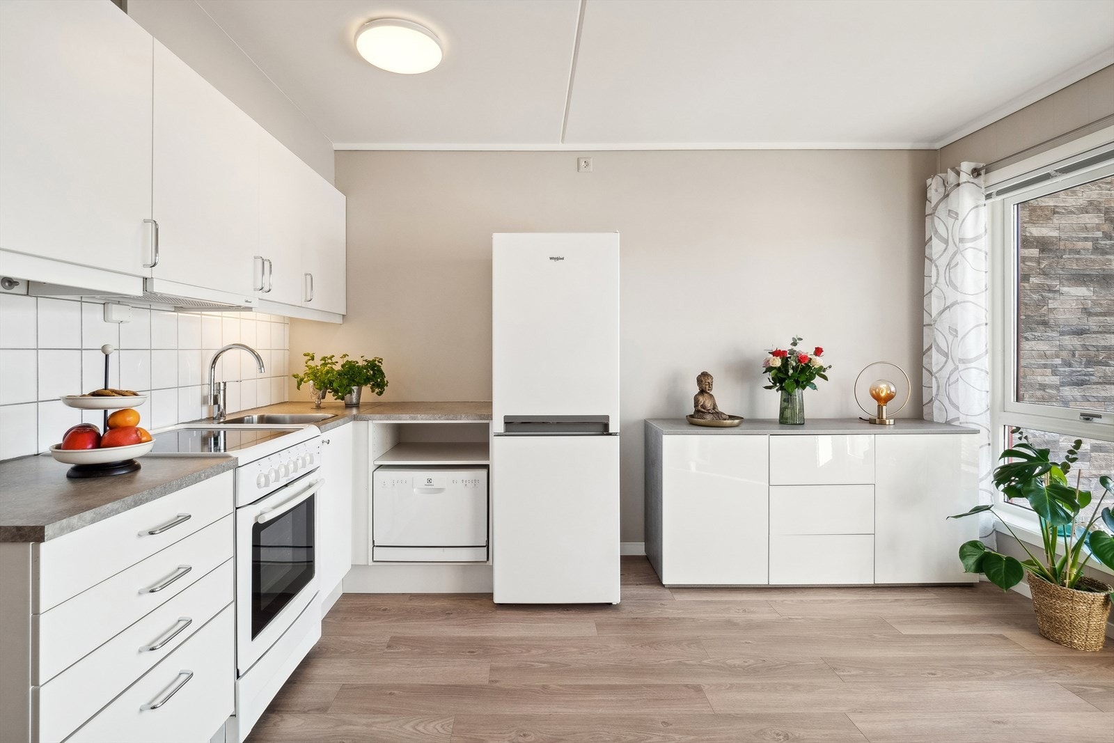 Kjøkkeninnredningen har hvite glatte fronter og benkeplate av laminat. Galleribilde