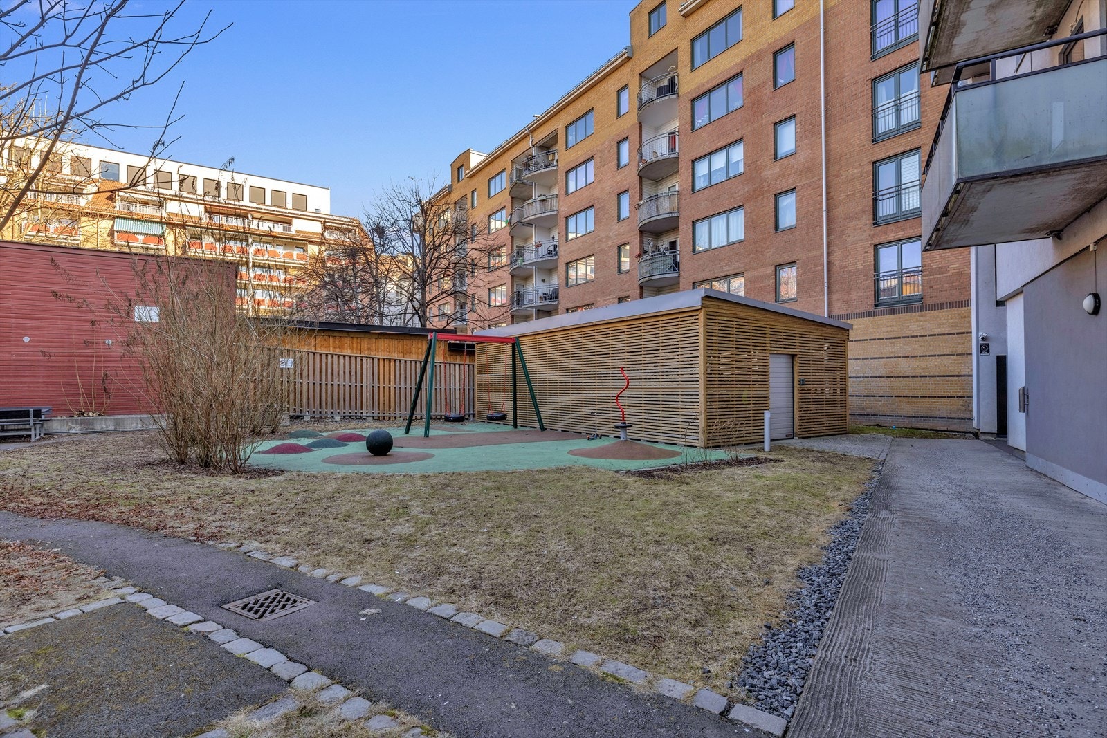 Lukket og velholdt bakgård med flere sittegrupper og velholdt beplantning. Galleribilde